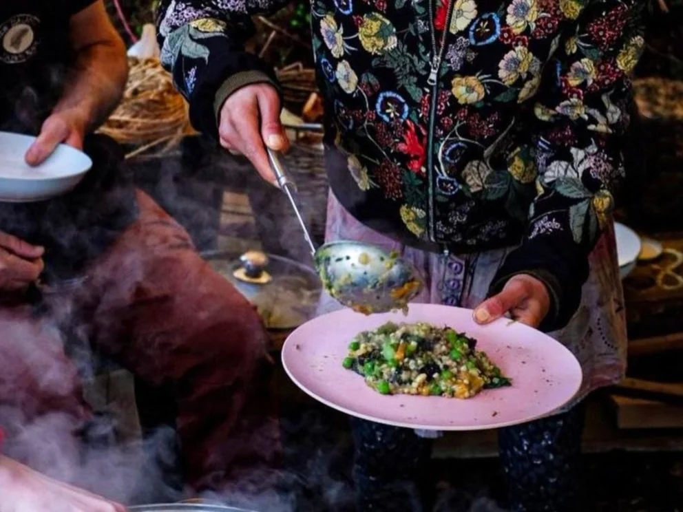 Person in floral jacket serving food onto pink plate