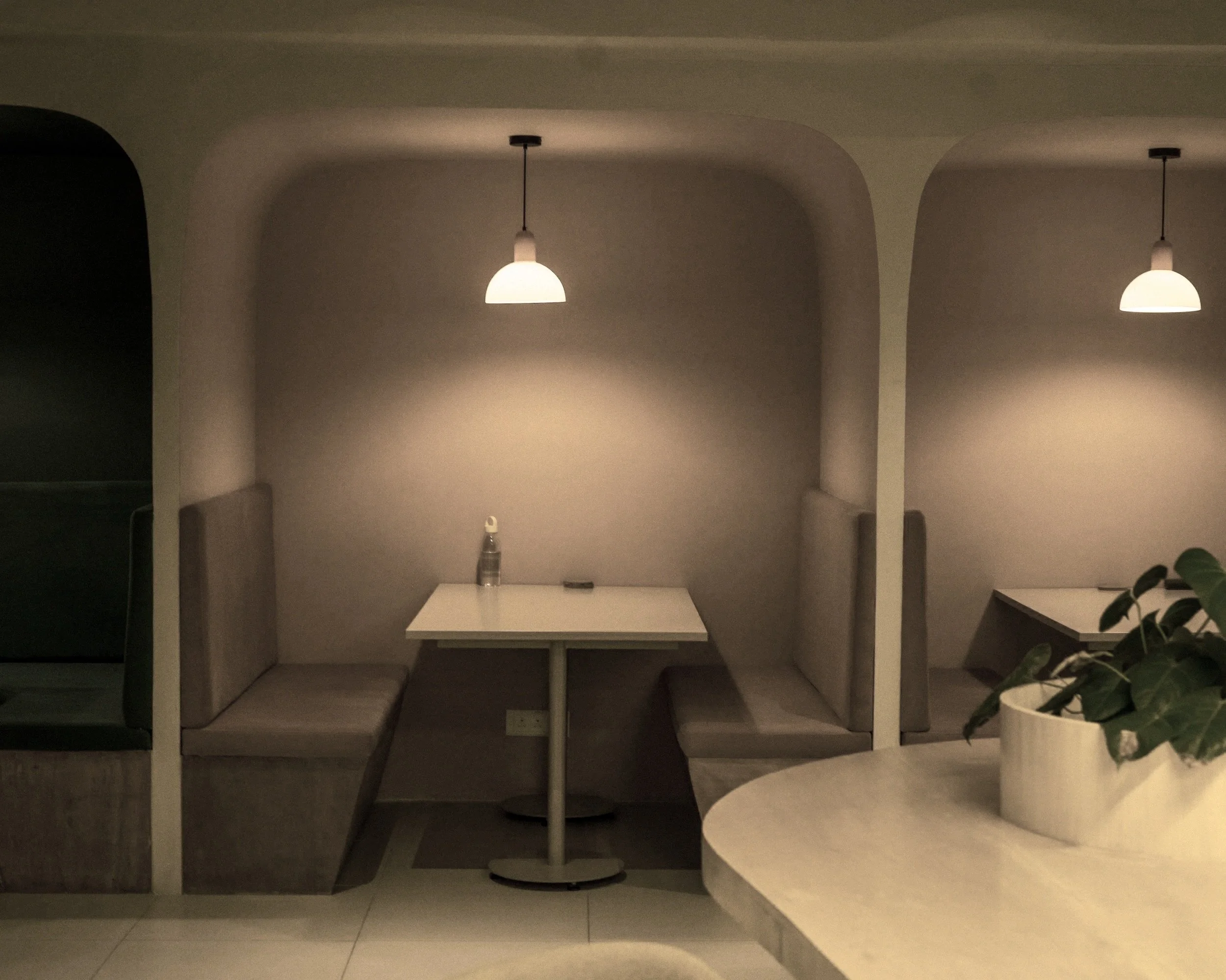 Empty restaurant booth with flat wooden benches and a single hanging light shing down.