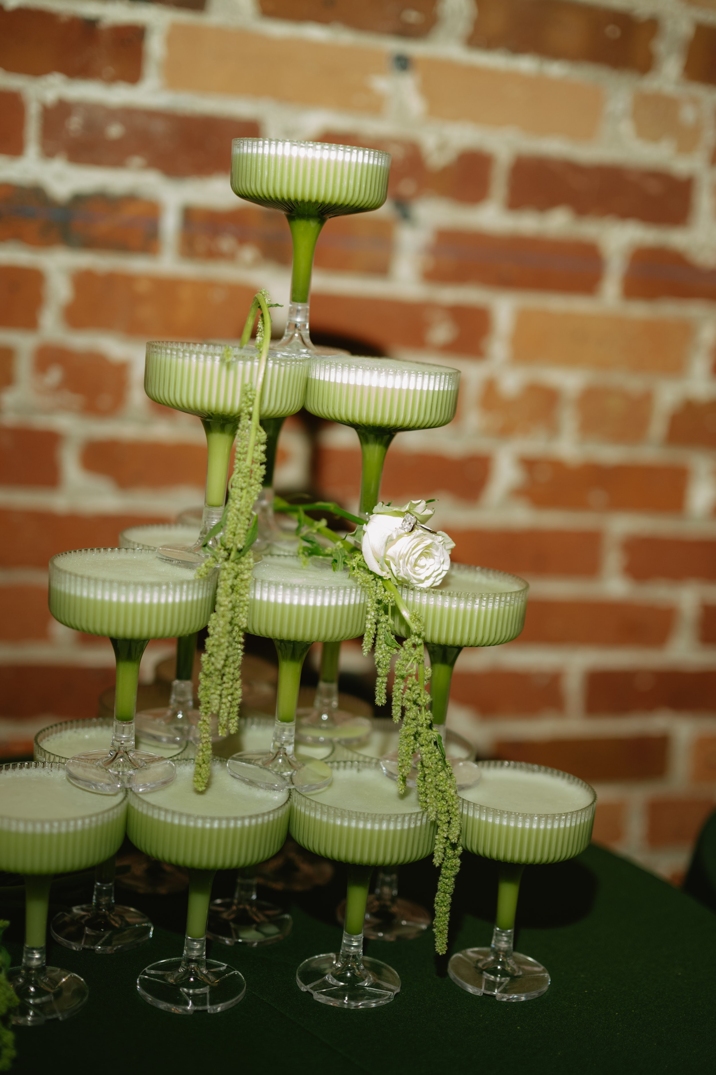 Green tea light candles arranged in a pyramid-shaped display on a table with a brick wall background.