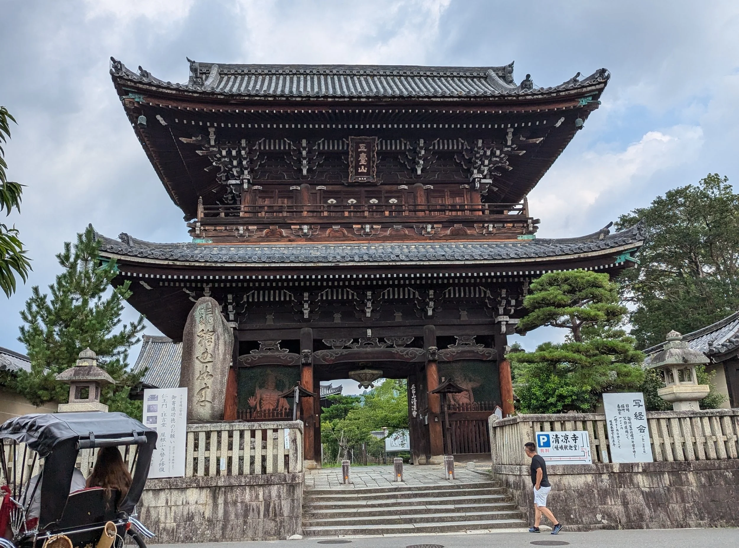Traditional two-story wooden temple gate in Japan with a rickshaw waiting out front