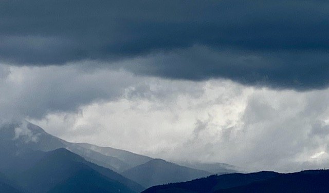 Dark storm clouds over a mountain range with low-hanging mist.