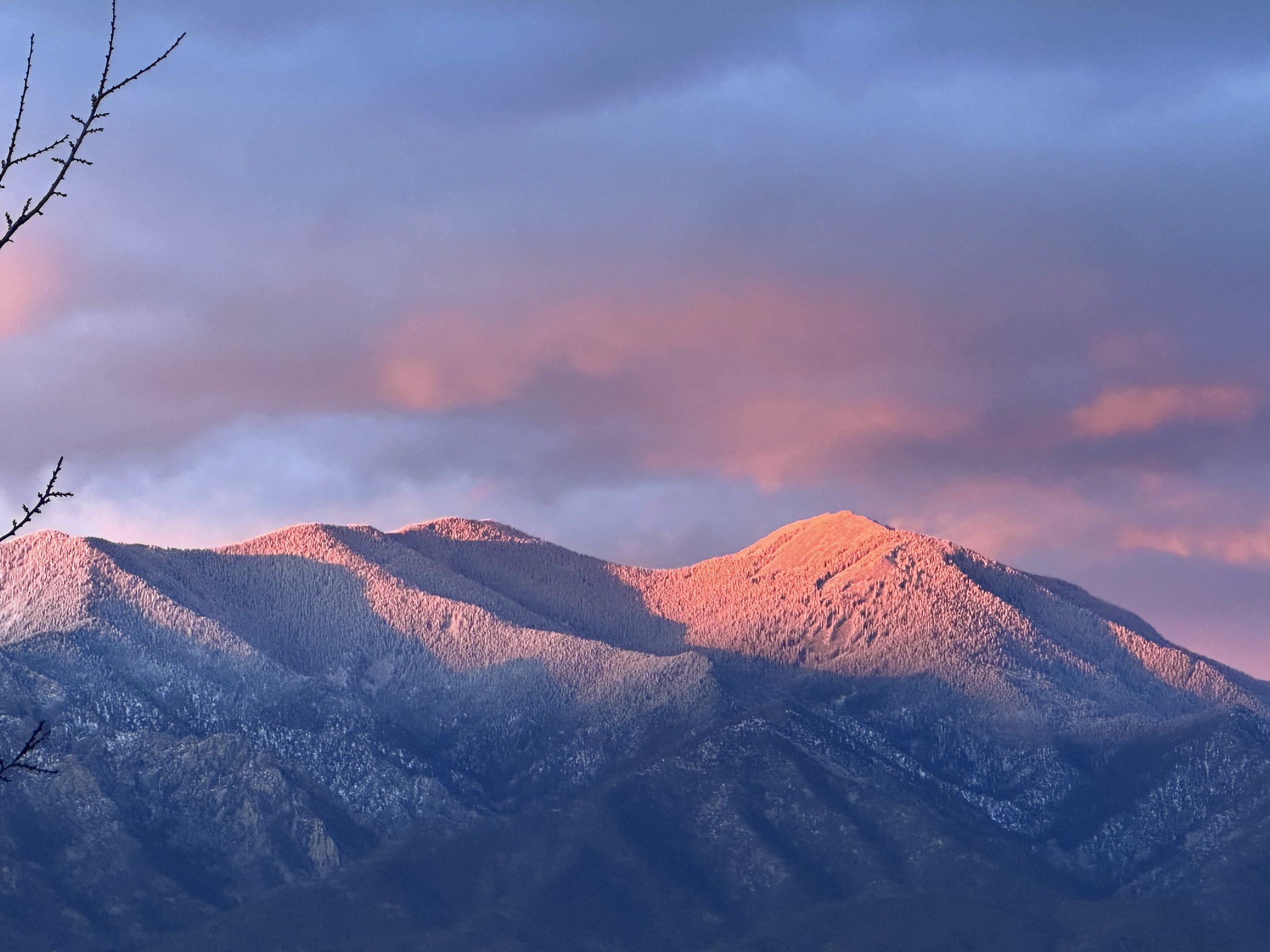 Allen glow on Pueblo Mountain, Taos, at sunset with snow-capped peaks and colorful sky