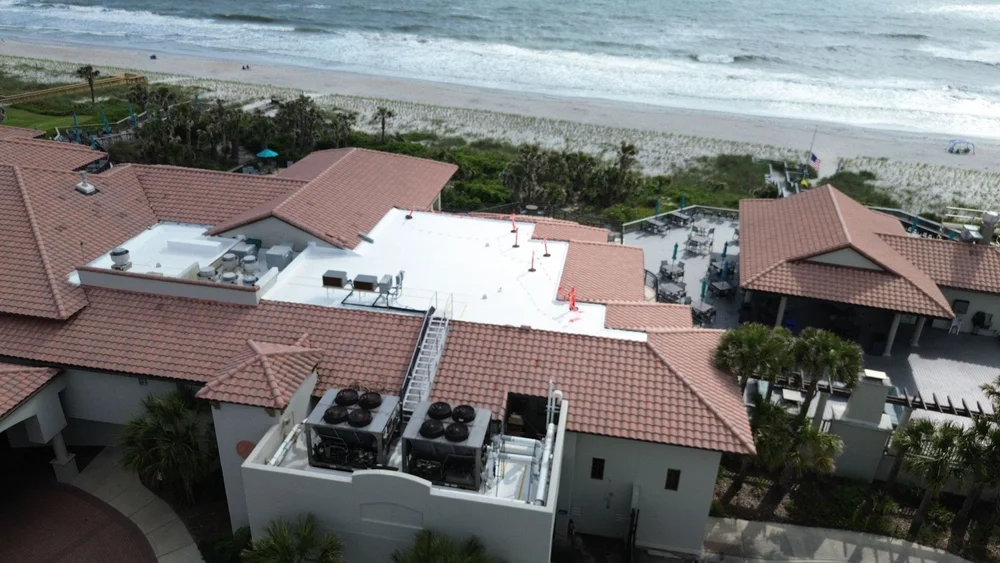 Aerial view of a TPO roof re-cover on a beachfront hotel by T. Conlan Roofing