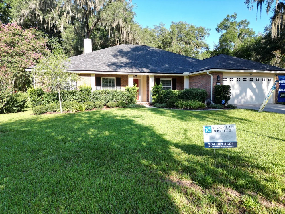 Single-story home with a new shingle roof and T. Conlan Roofing yard sign
