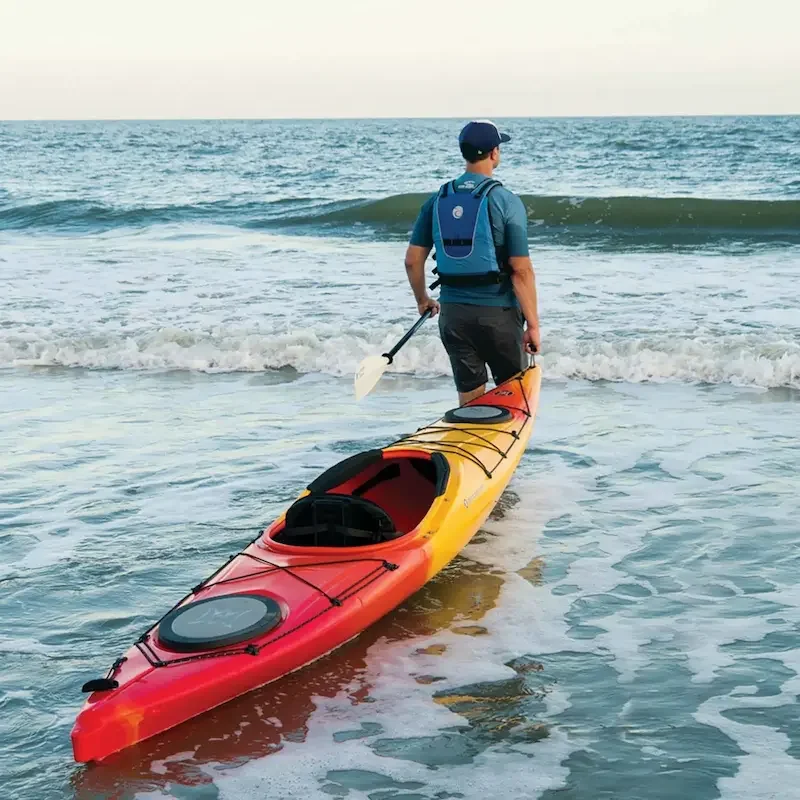 Image of man pulling the Perception Carolina 12 touring kayak into the ocean.