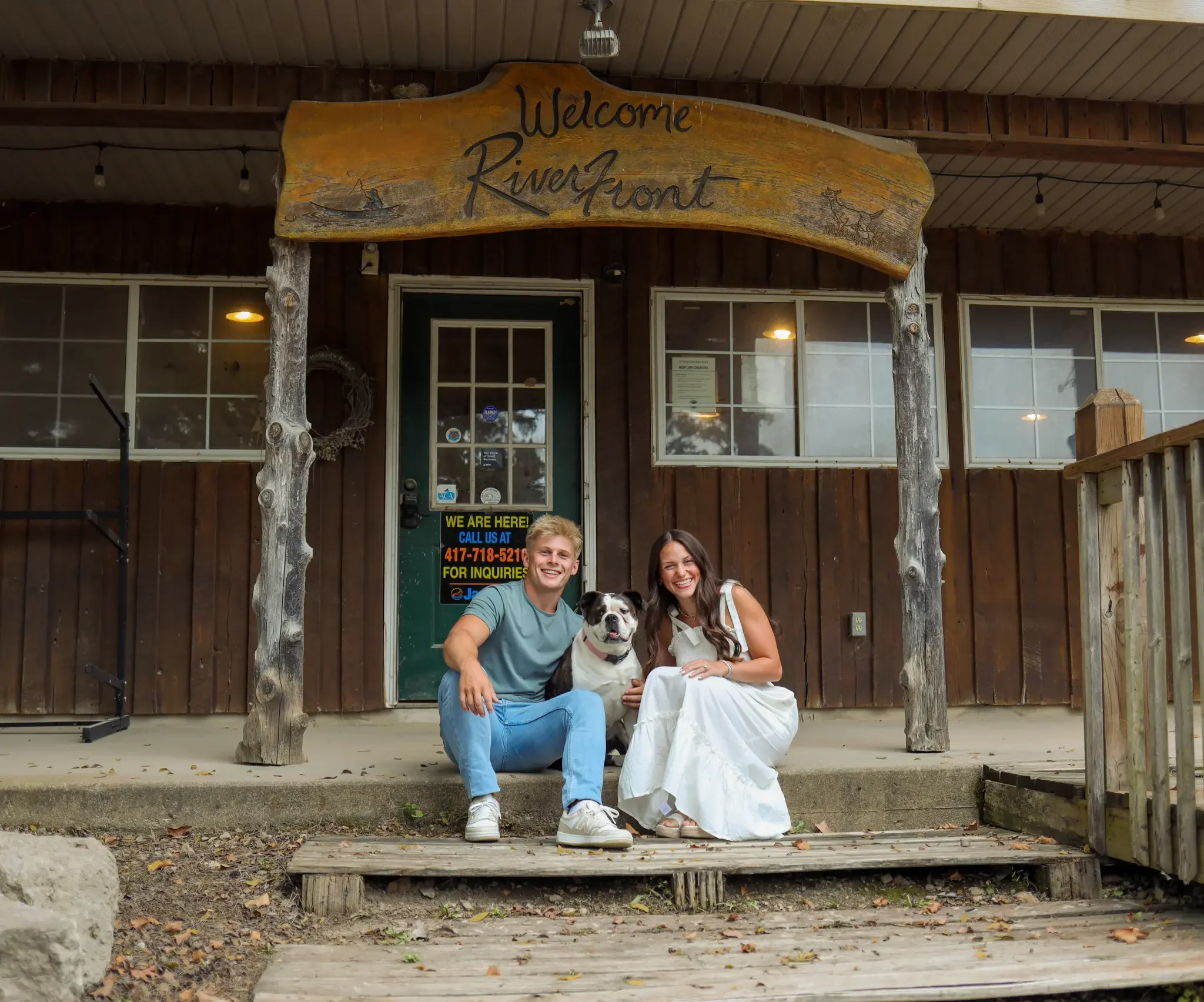 Owner, Jax sitting in front of the kayak shop with dog, Stomper, and wife Taylor.