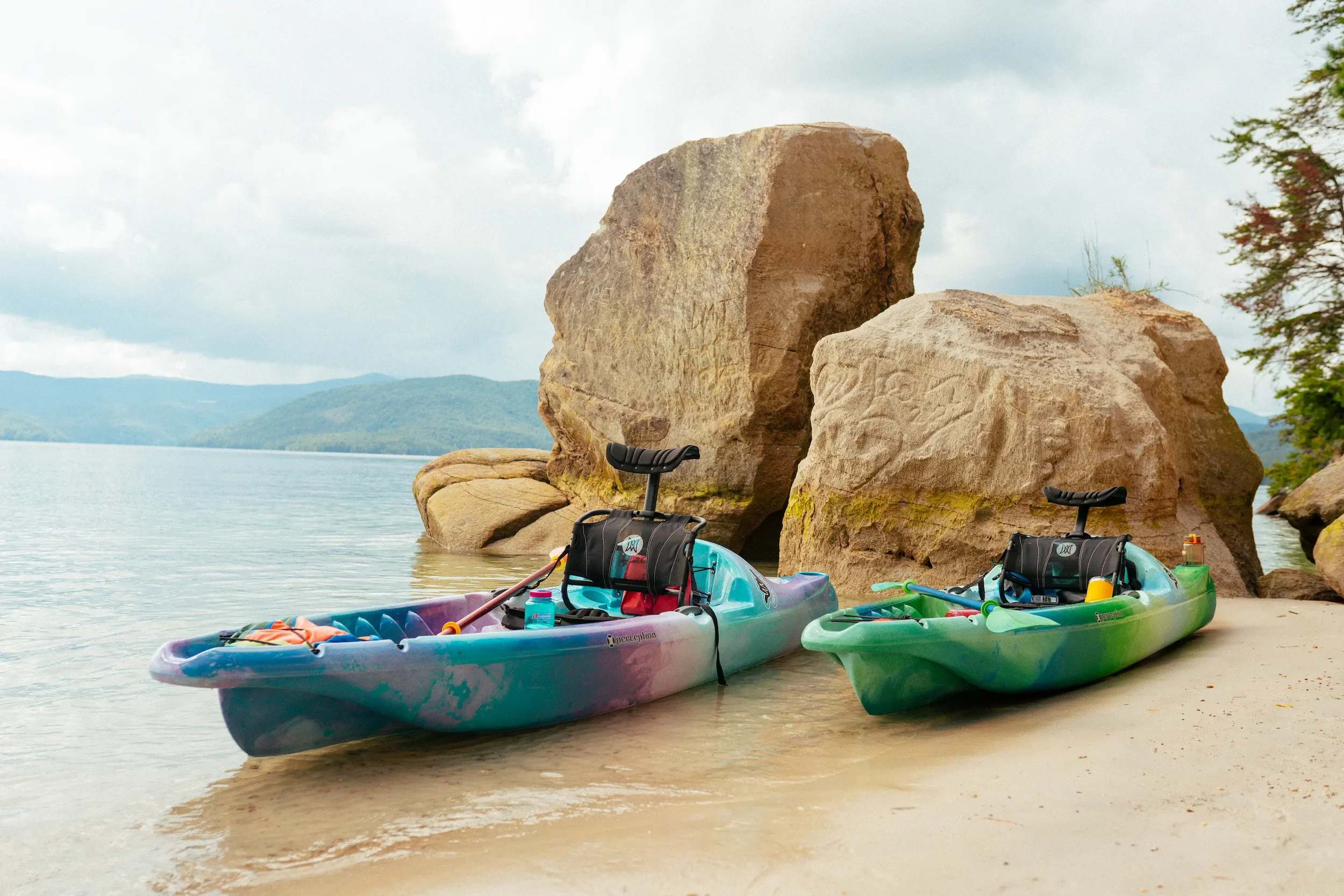 Two Perception Hangtime 11 kayaks pulled up on a sandy beach.