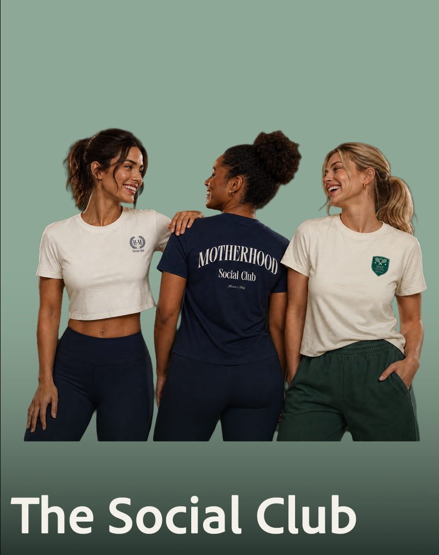 Three women smiling and talking, two wearing casual t-shirts and the woman in the middle wearing a navy t-shirt with "Motherhood Social Club" printed on the back. They are standing against a green background with "The Social Club" written at the bottom.