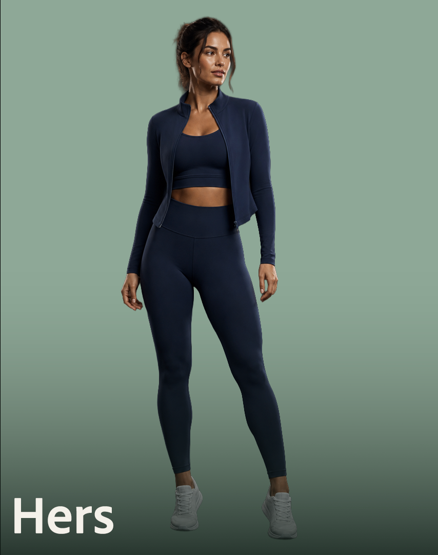 A woman standing against a light green background, wearing a navy blue athletic jacket, sports bra, and leggings, with gray running shoes.