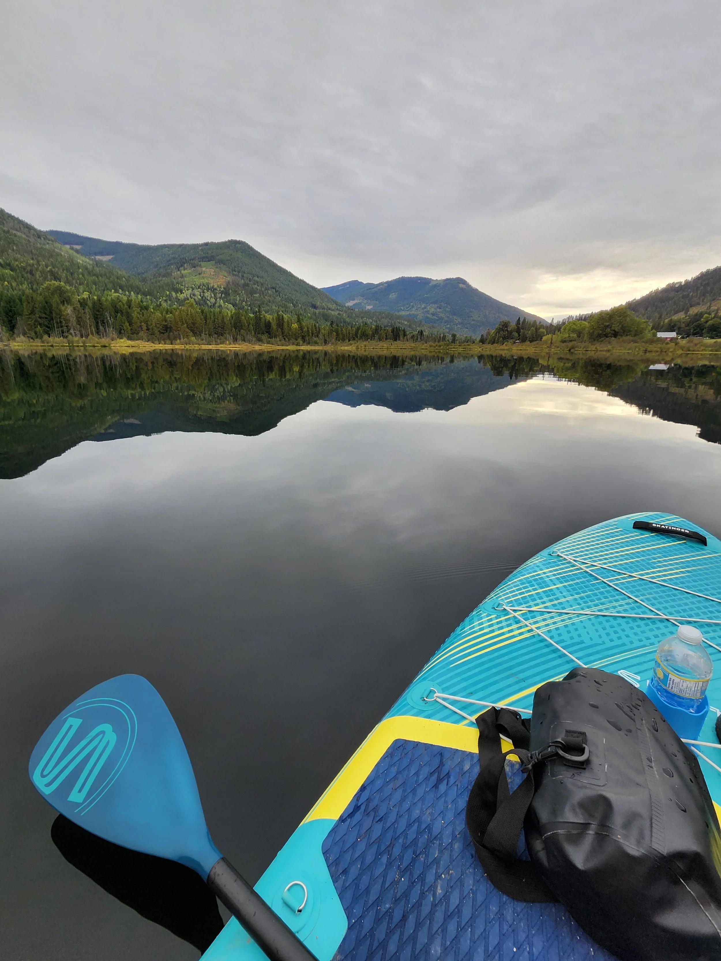 Peaceful mountain lake with a paddleboard, representing emotional healing, mindfulness, and personal growth through counselling.