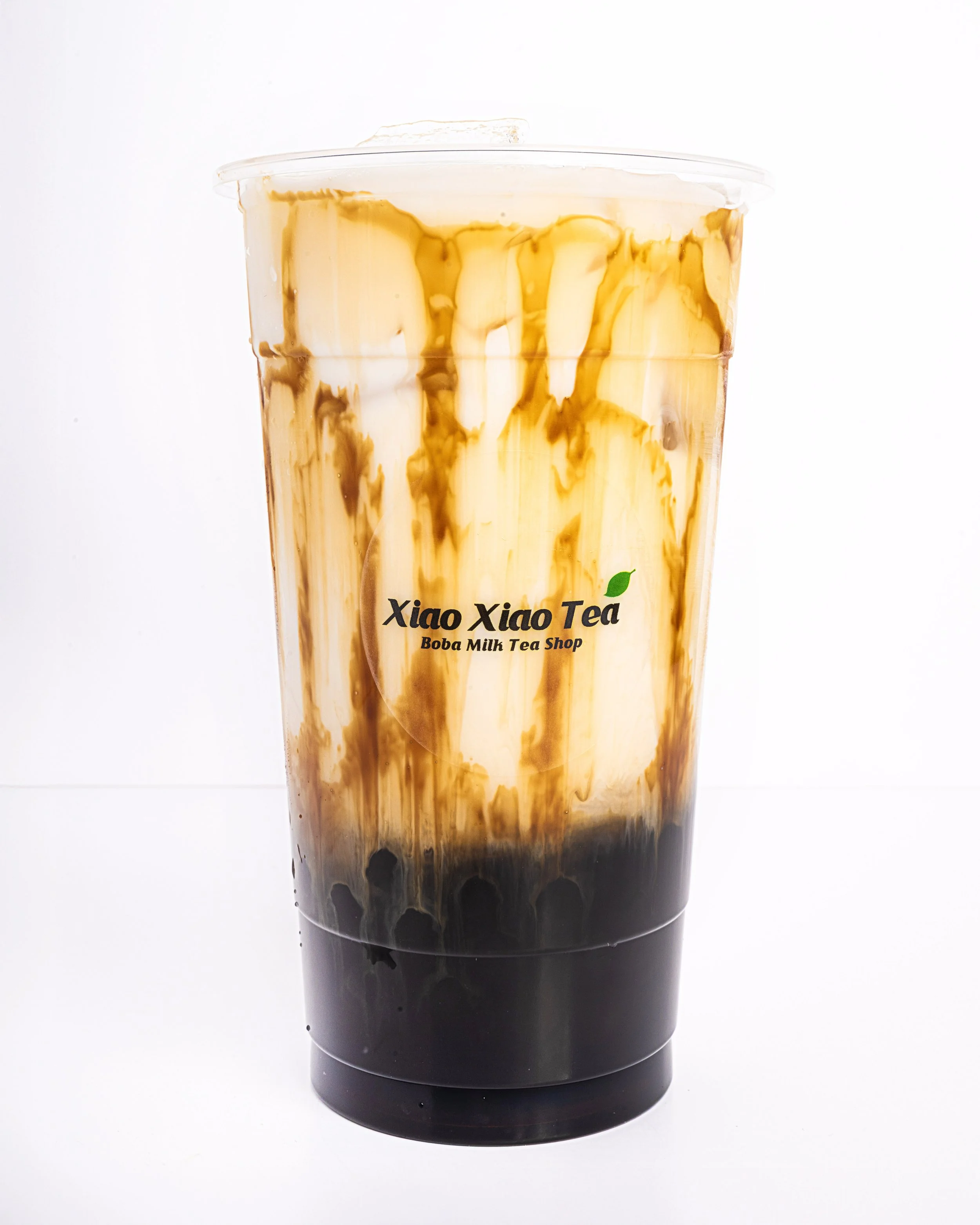 A brown sugar boba latte with milk on the top, boba at the bottom, and drizzles of brown sugar syrup around the sides.