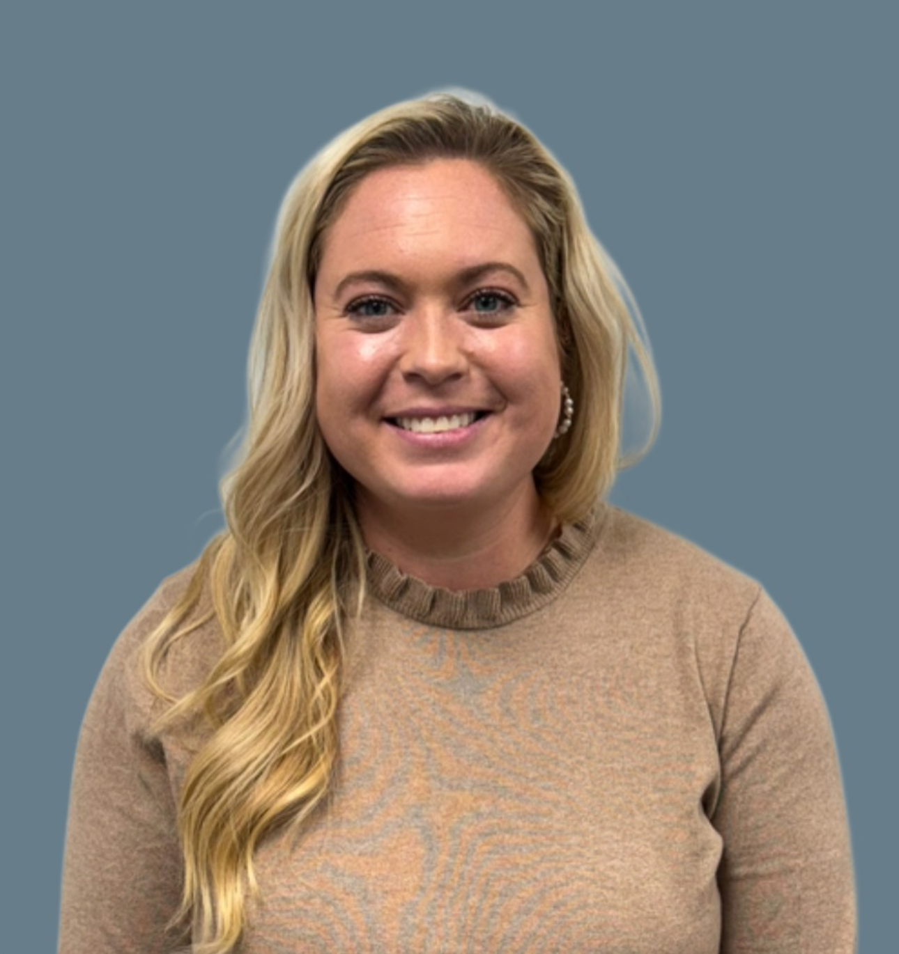 Smiling woman with long blonde hair and beige sweater against blue background.