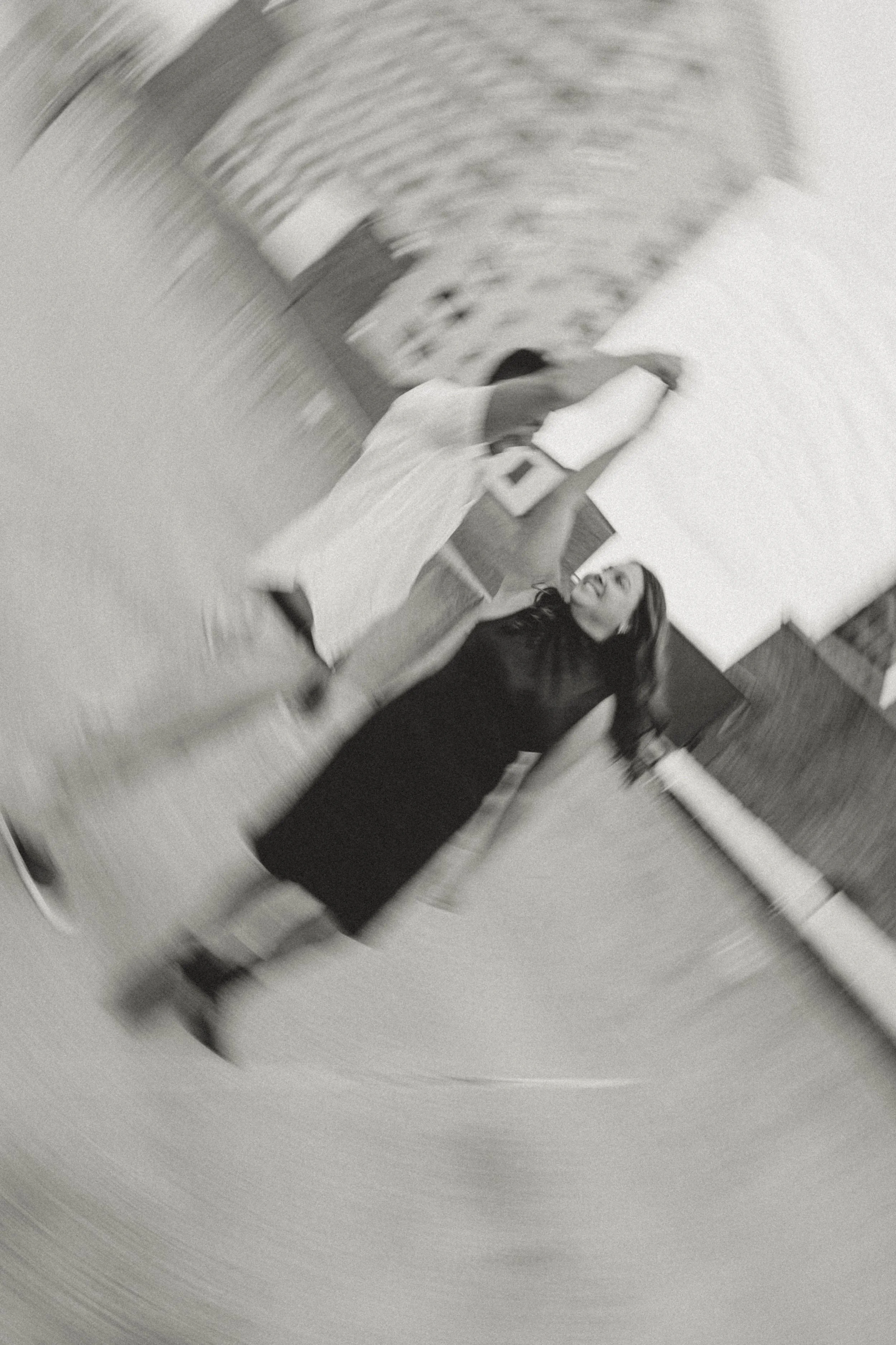 A woman and a man are dancing closely in a room. The photo is in black and white with a swirl effect, creating a sense of motion.