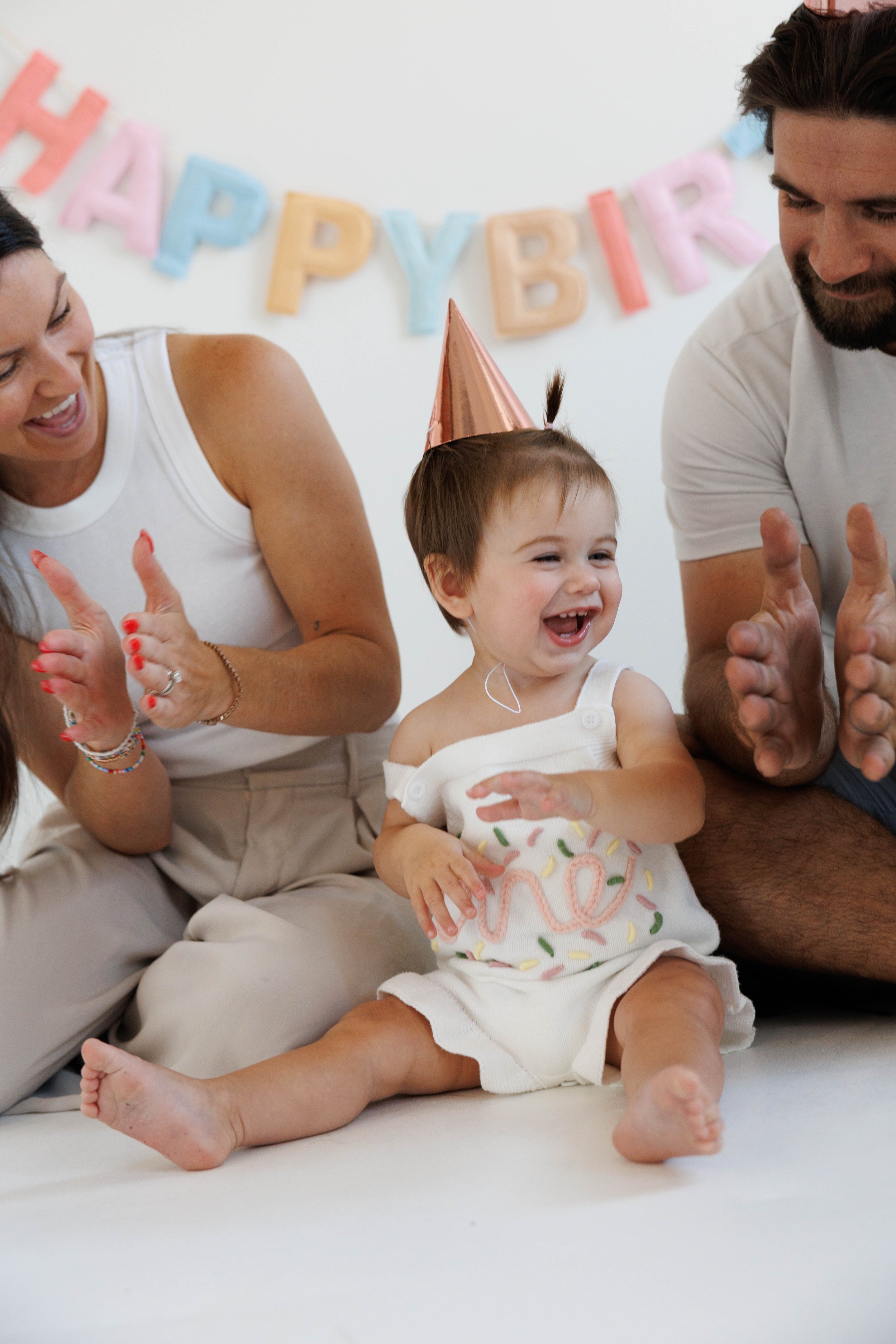 Children celebrating a birthday with party hats, smiling and clapping, with a "Happy Birthday" banner in the background.
