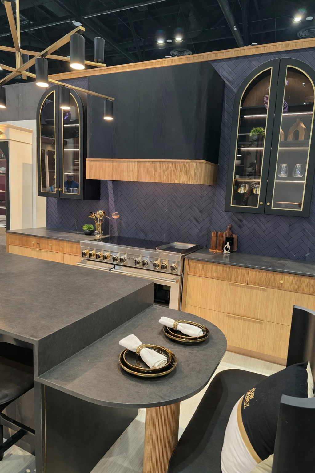 Luxury hangar home kitchen design featuring navy cabinetry, light wood finishes, brass accents, and herringbone backsplash from KBIS 2026.
