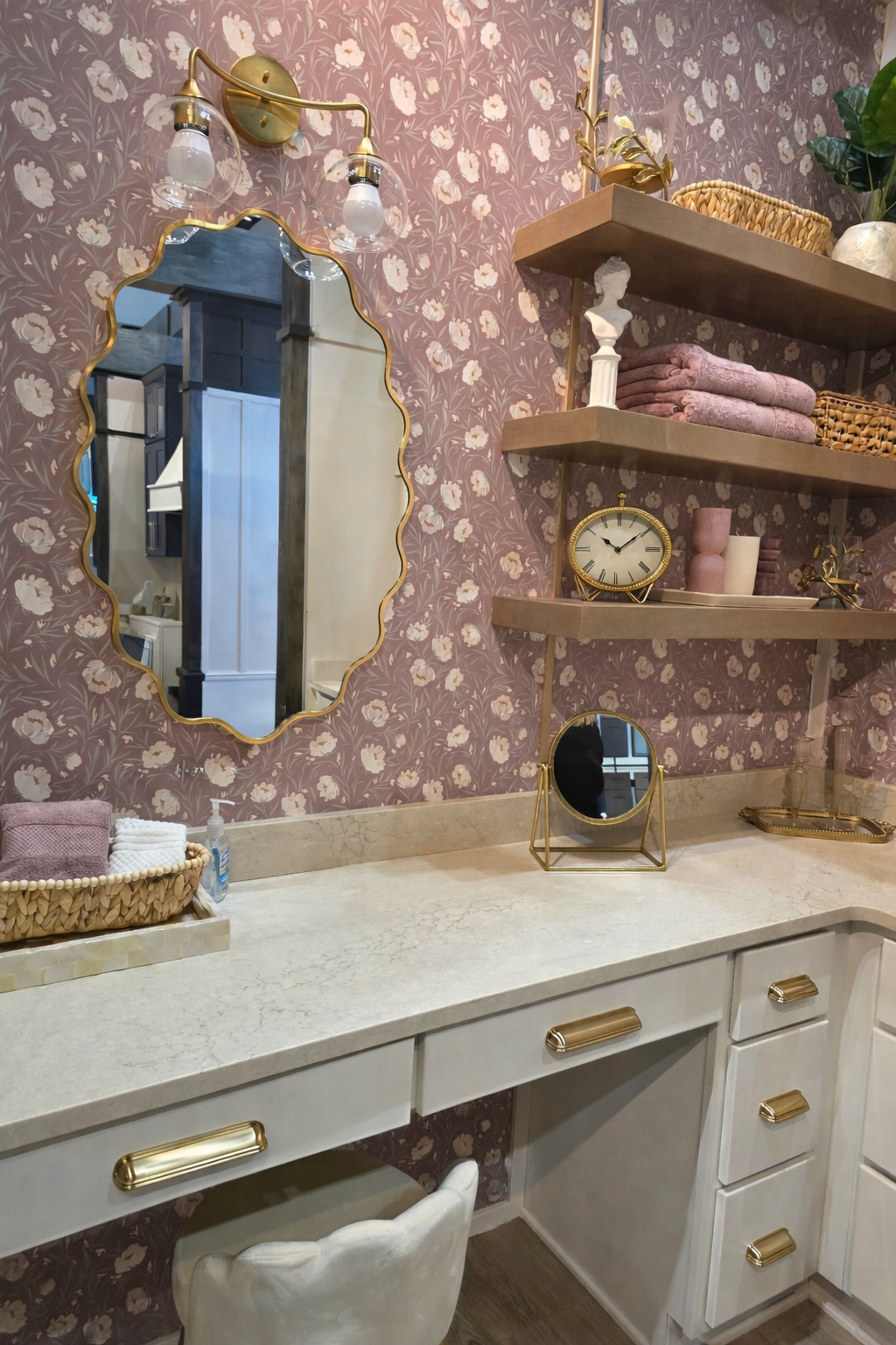 Luxury hangar home bathroom vanity with floral wallpaper, brass hardware, marble countertop, and styled floating shelves.