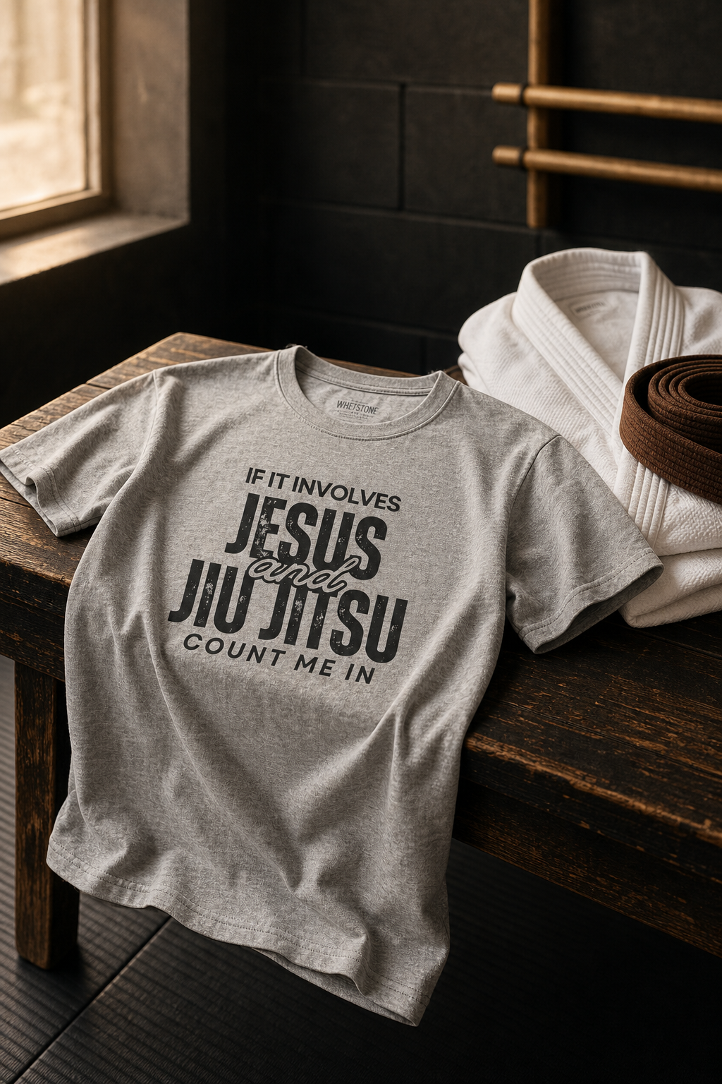 Naturally draped heather gray Jesus and Jiu Jitsu Christian T-shirt beside a white gi and brown belt.