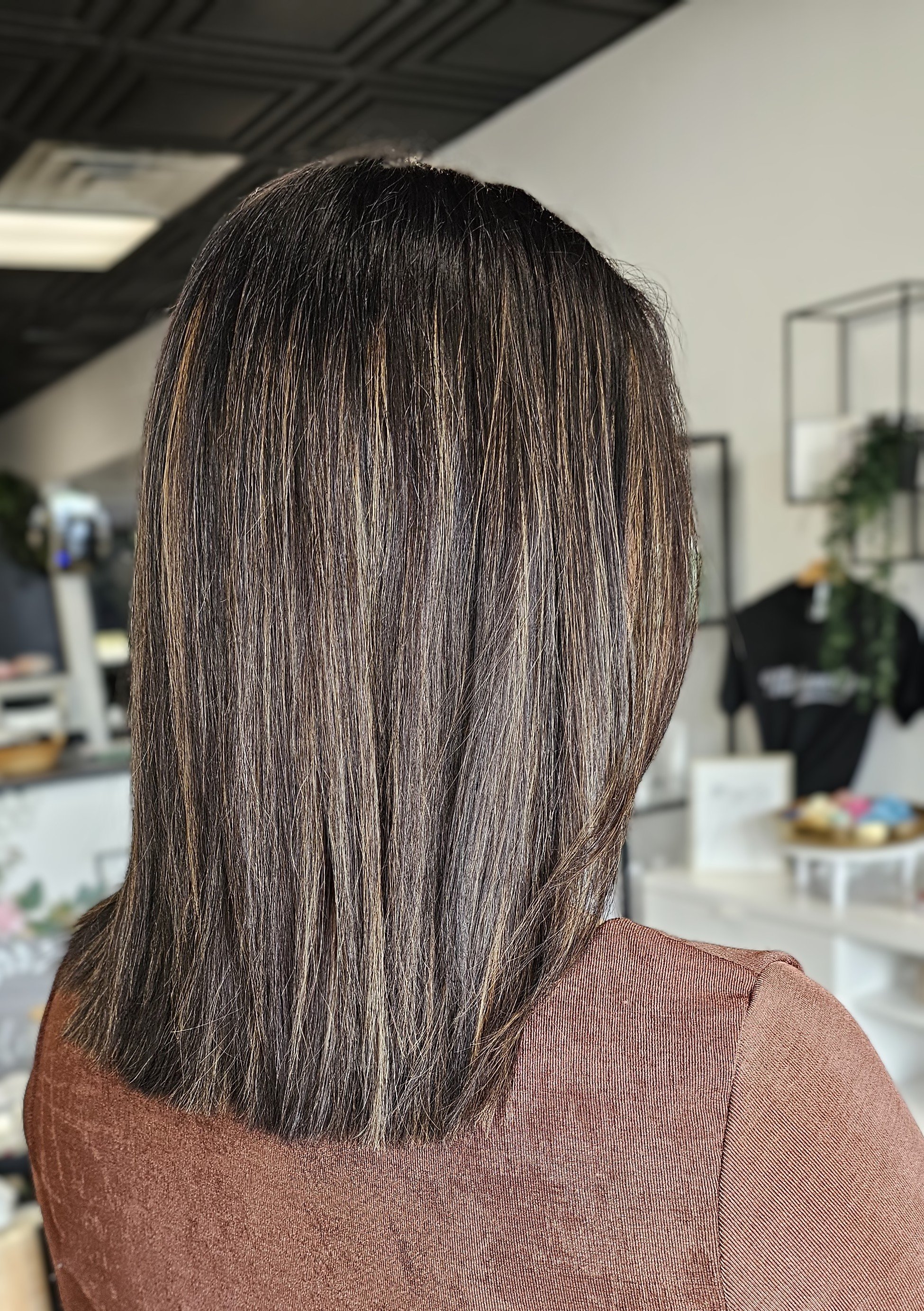 Woman with straight brown hair with highlights in a salon.