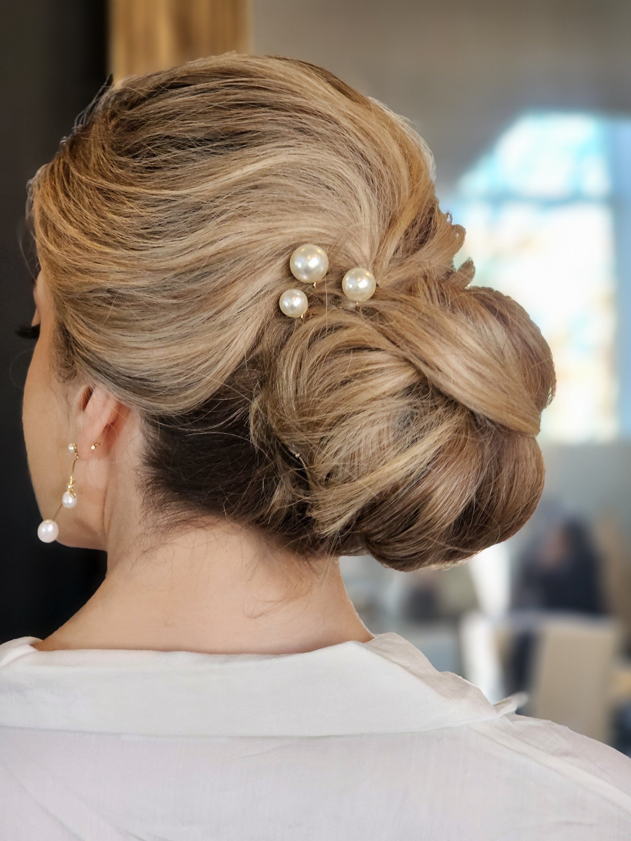 Woman with an elegant updo hairstyle adorned with pearl hairpins