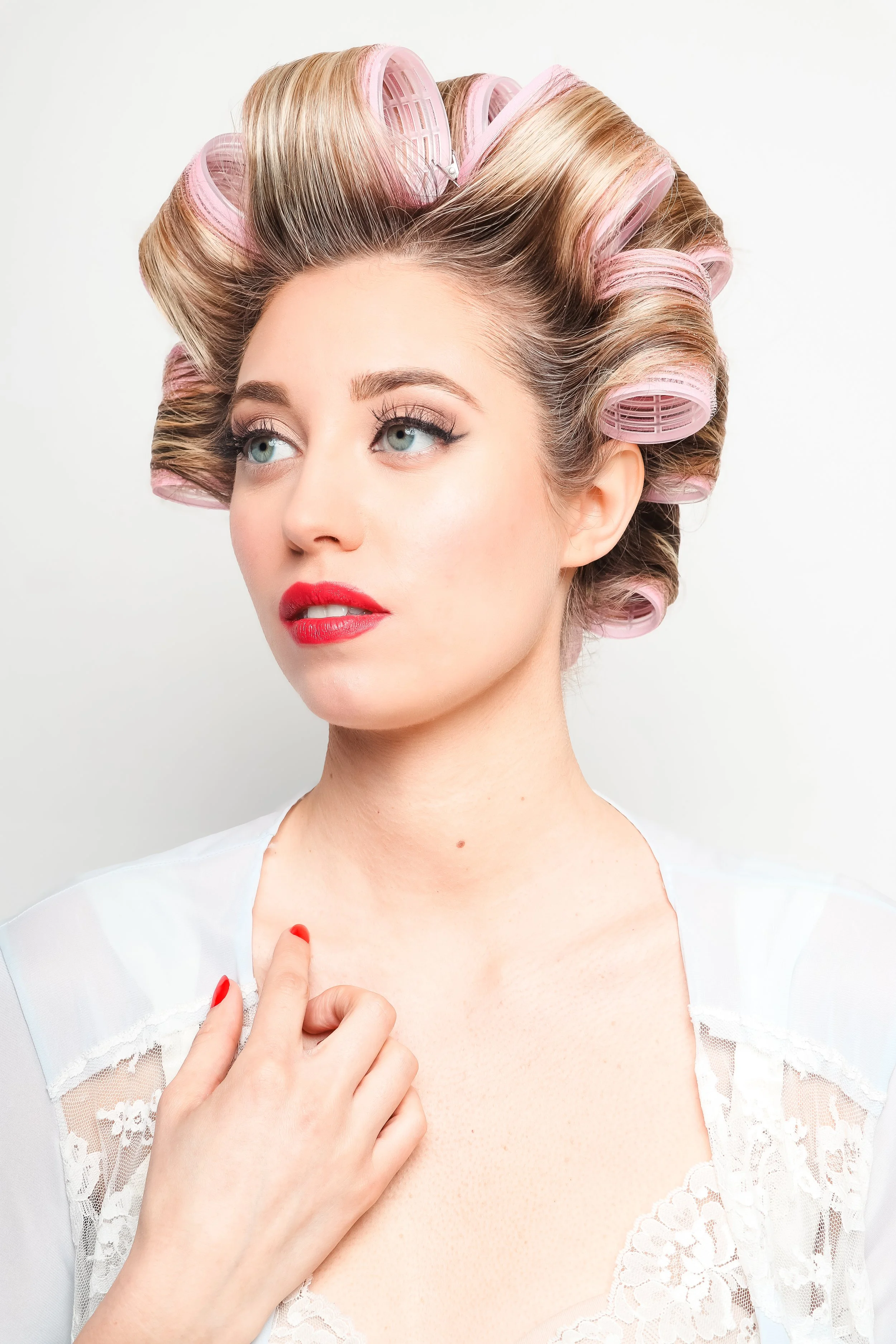 woman with rollers in her hair and retro style makeup in a camisole and red nails