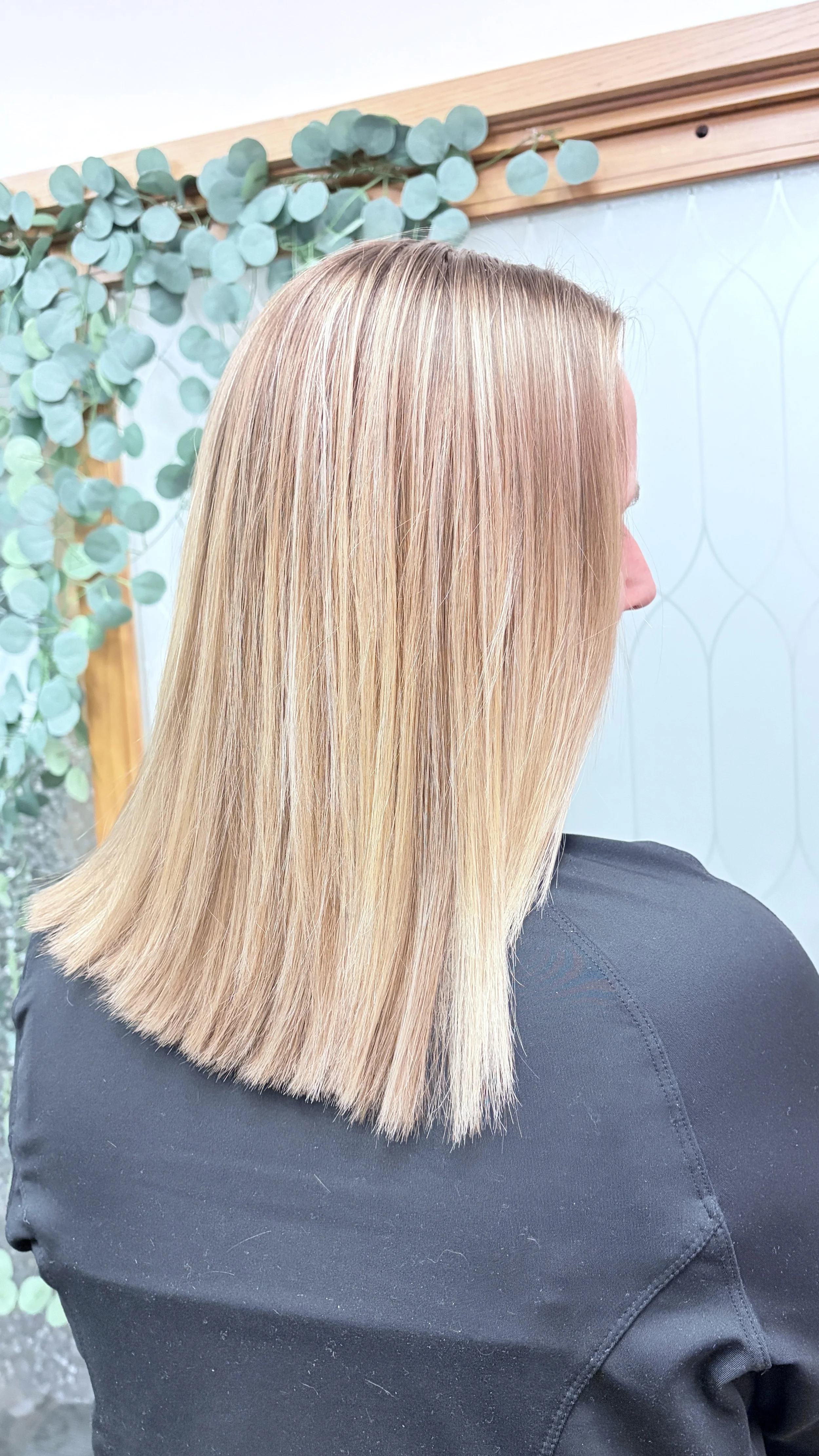 Blonde haired woman standing near a door with green vines.