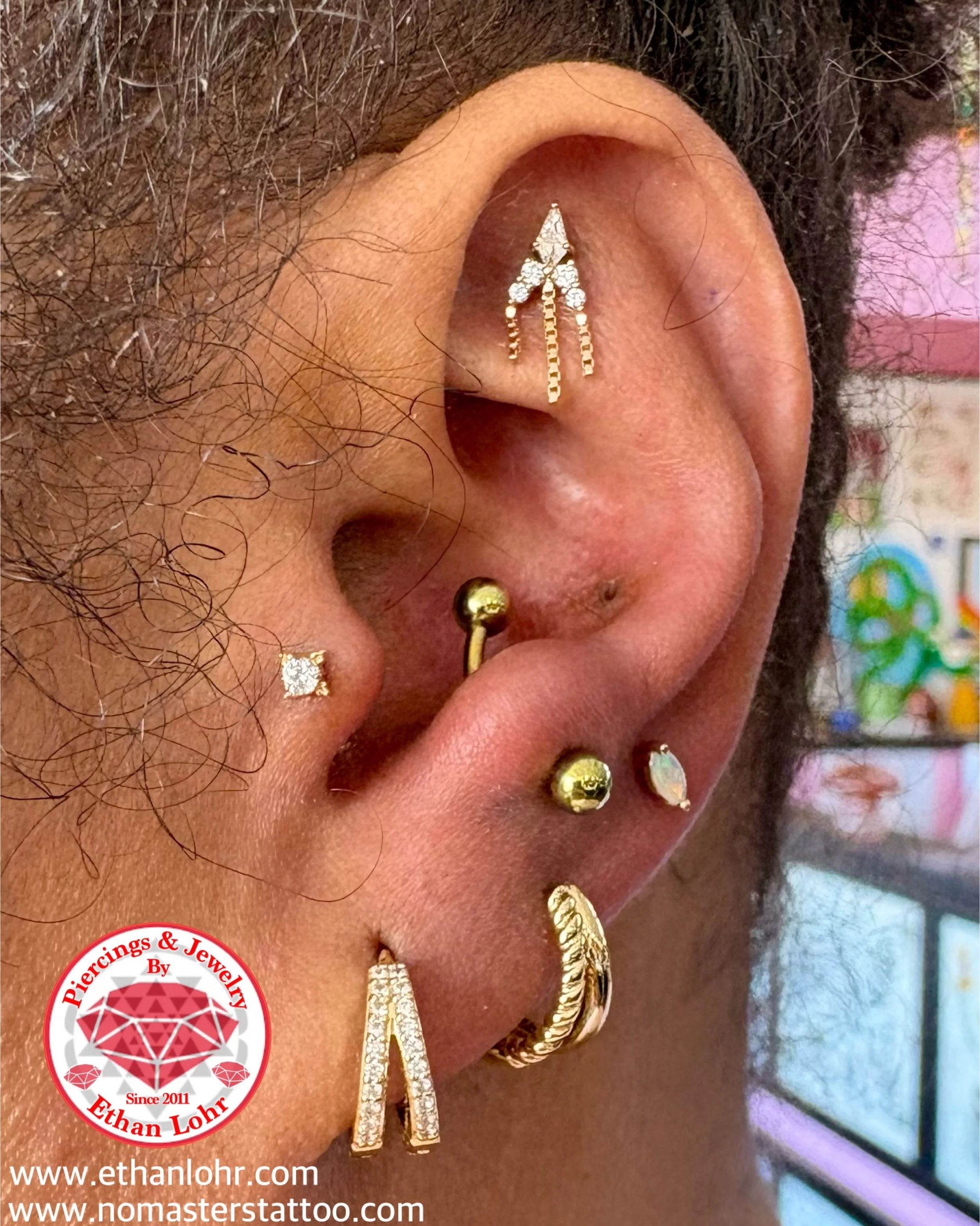 Fresh Tragus with a Zia in solid yellow gold with cz and an anti-Tragus with golden anodized titanium curved barbell. We also did some downsizing and upgrading. We installed the zuri with opal in yellow gold in her earlobe and the Antoinette in yello