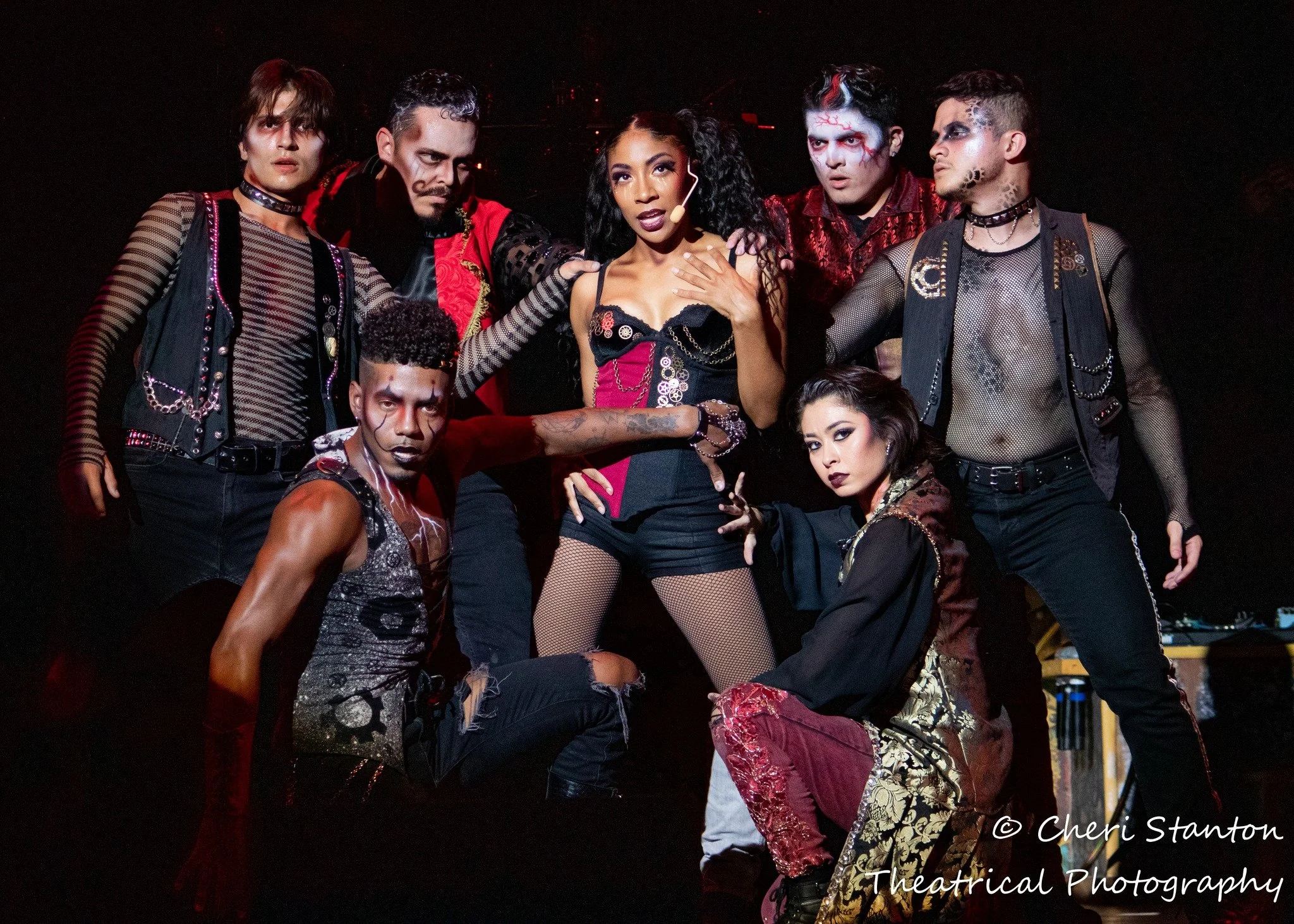 An ensemble cast in dark vampire and gothic performance costumes with fishnet and studded details poses together for Dr. Diabolical's Monster Mash Bash