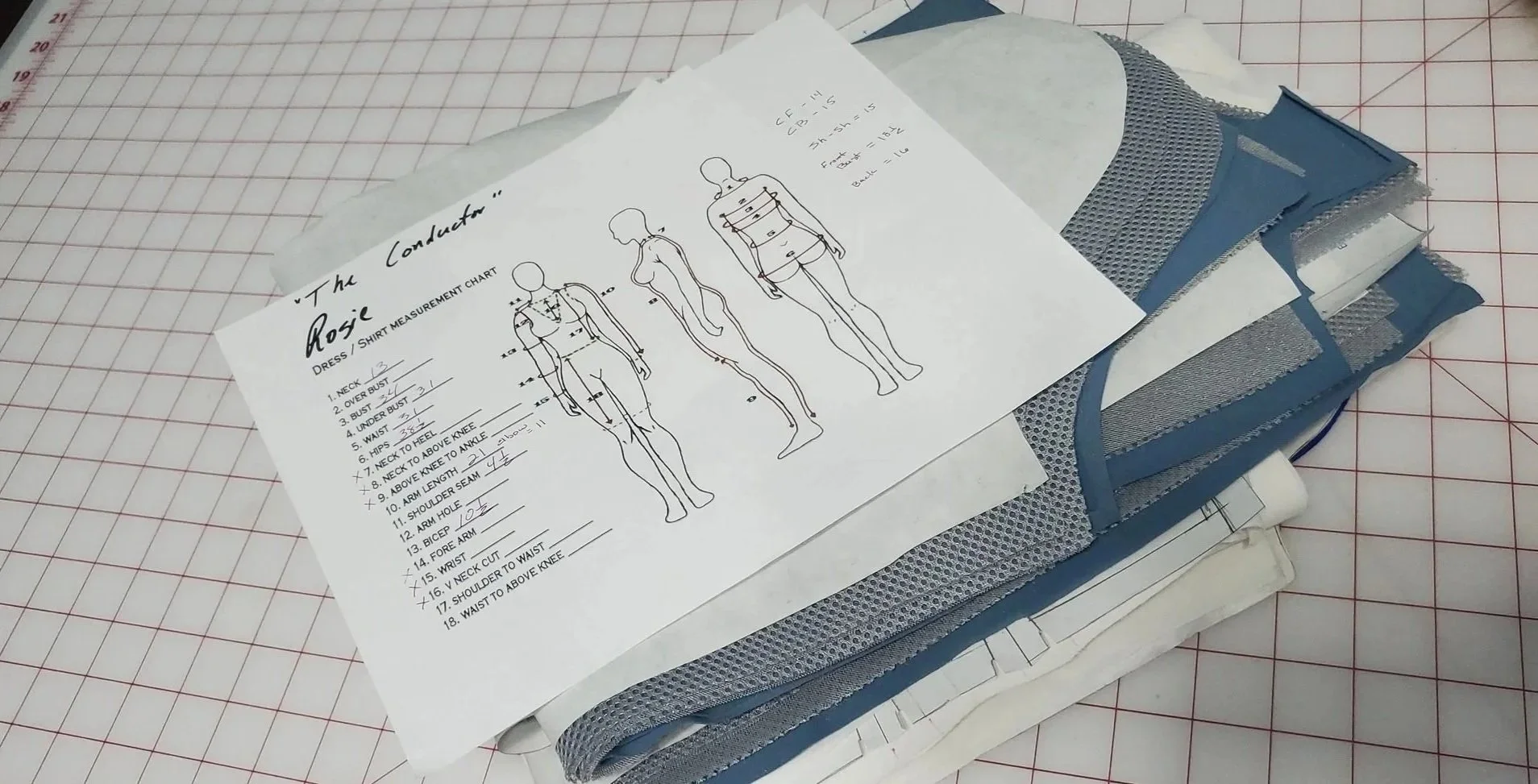 Pattern charts and fabric swatches for making a costume, placed on a cutting mat with red measurement grid lines.