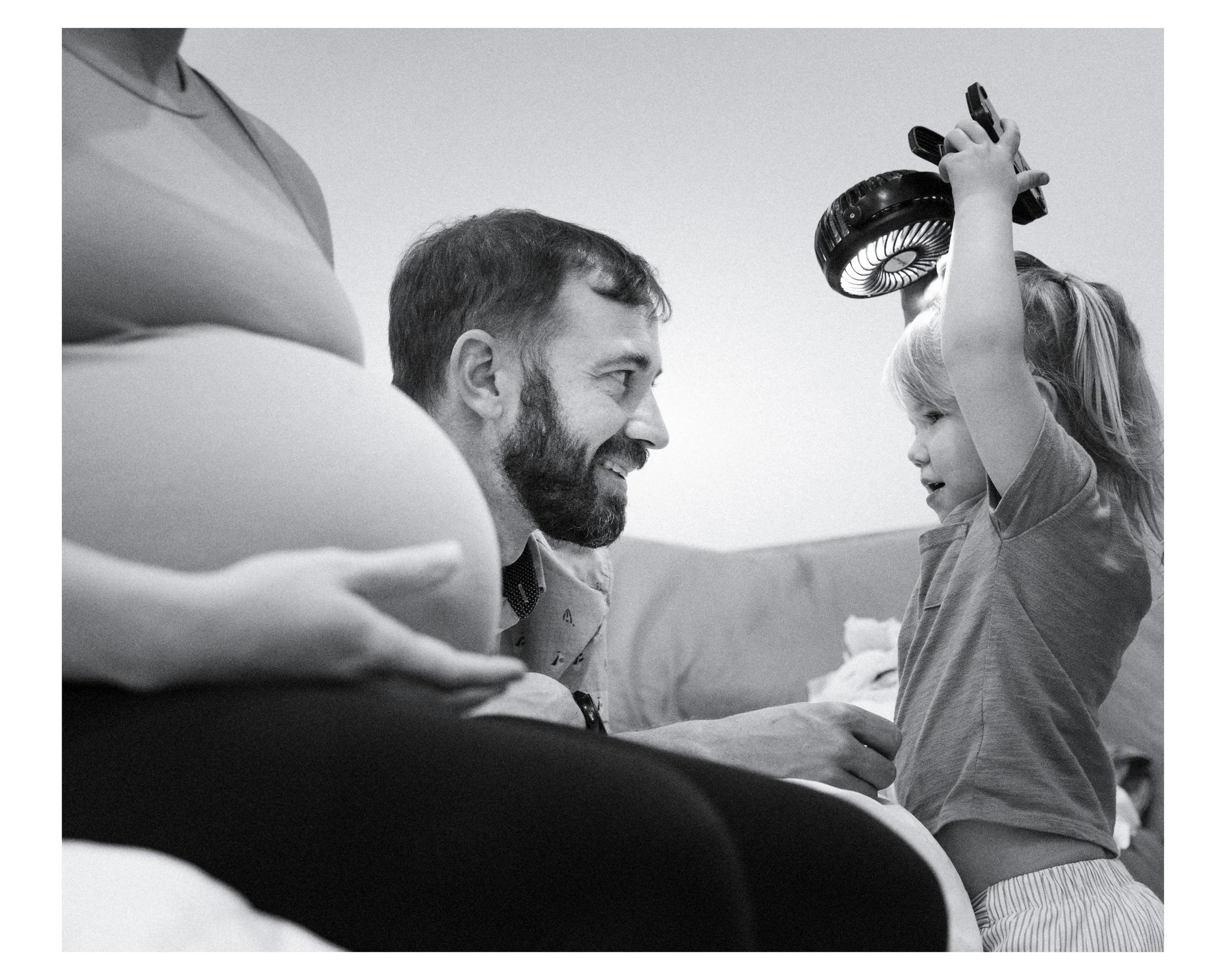 parents play with their little girl in the bedroom during a documentary family photo session in tucson