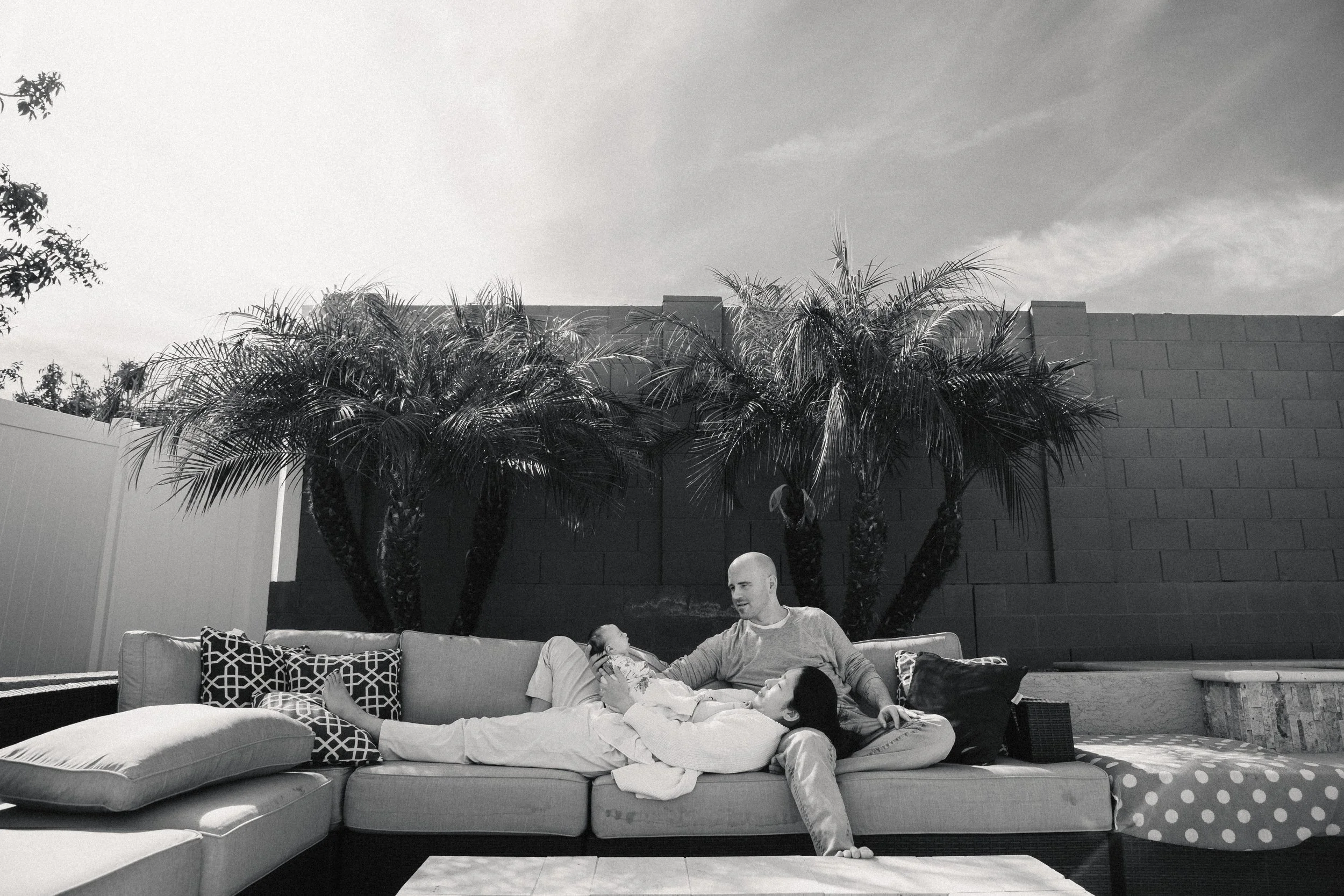 new family enjoys their backyard during a newborn photo session in phoenix