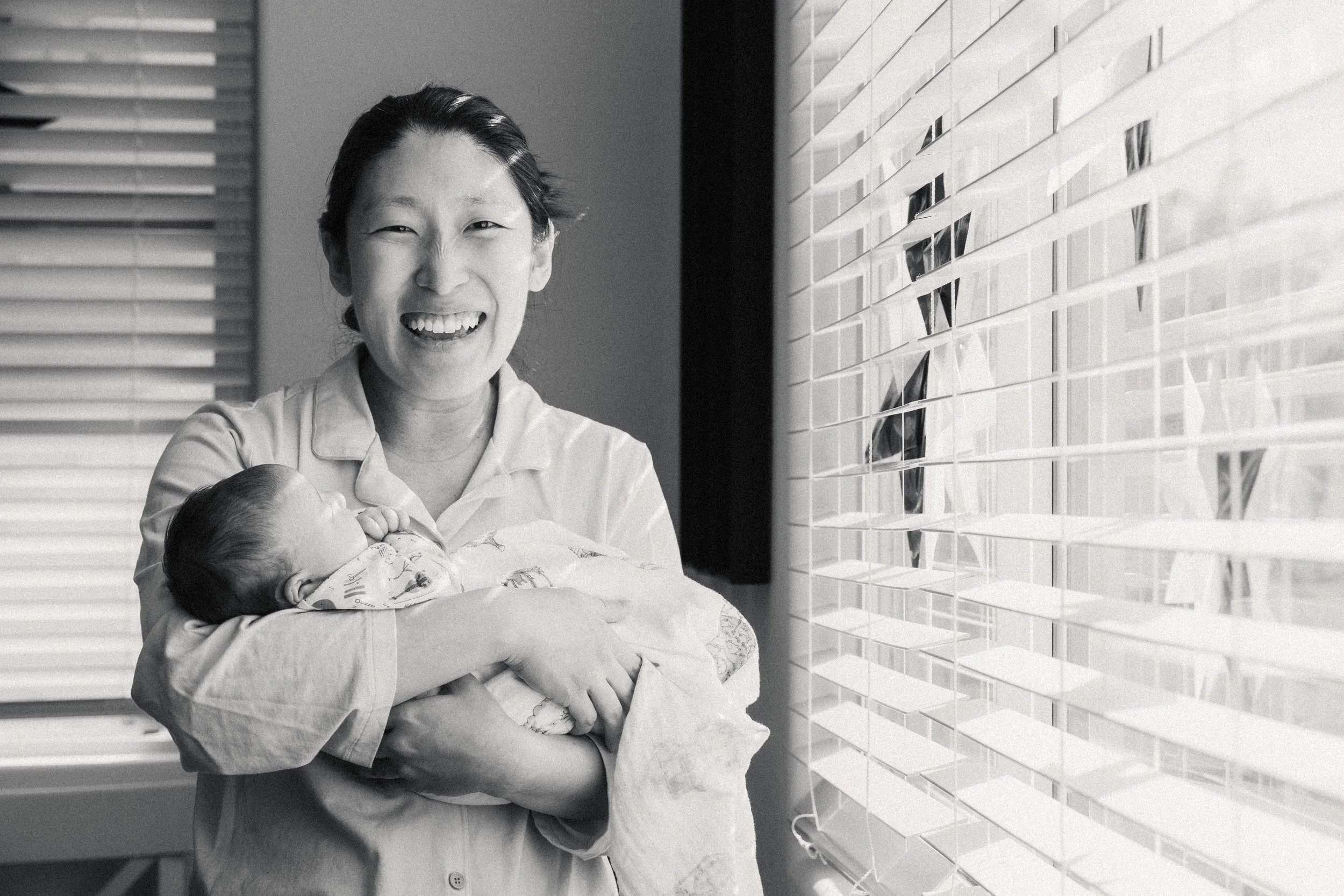 mom laughs while holding her newborn during photography session