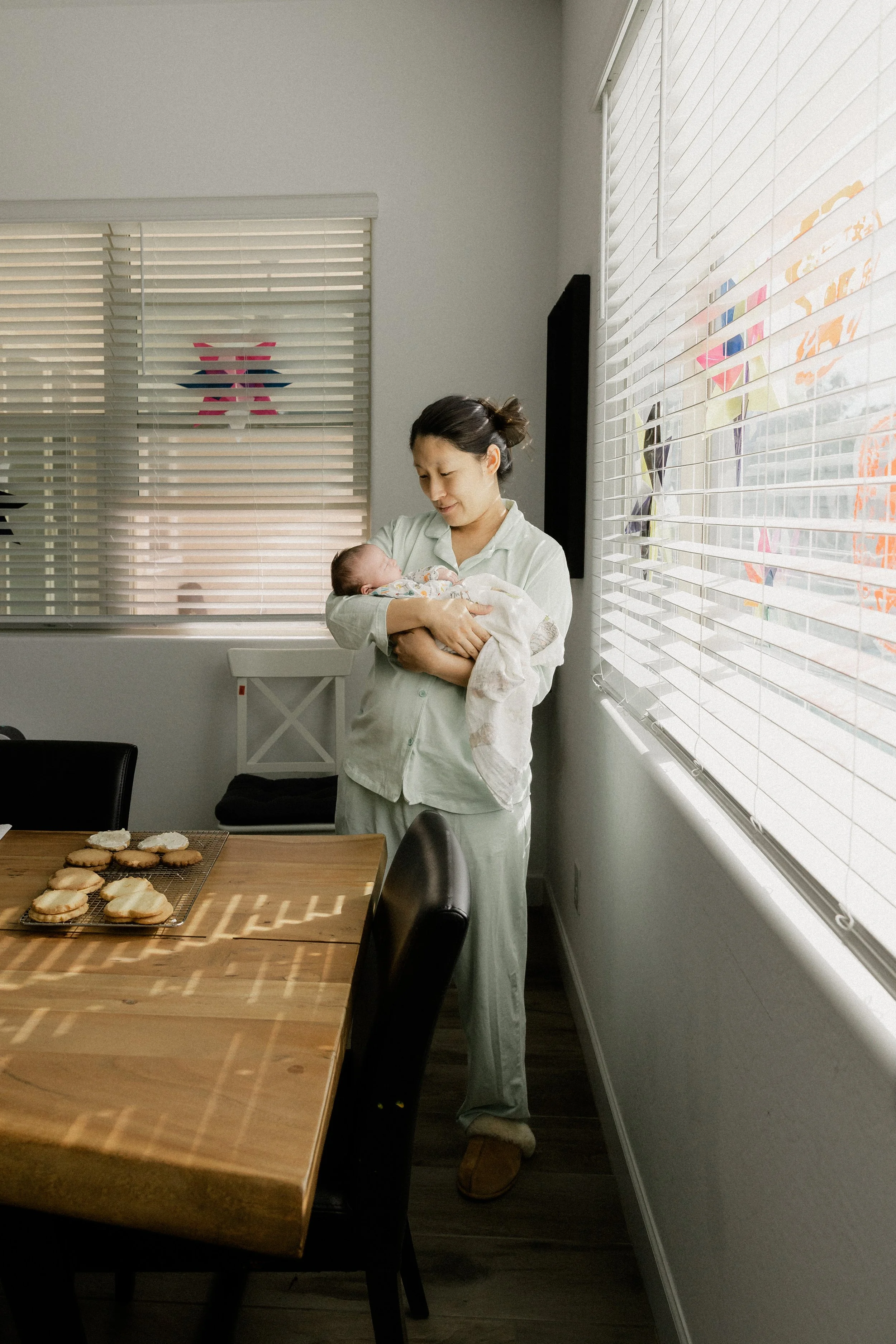 newborn and mom stand in dining room during an in home session in phoenix