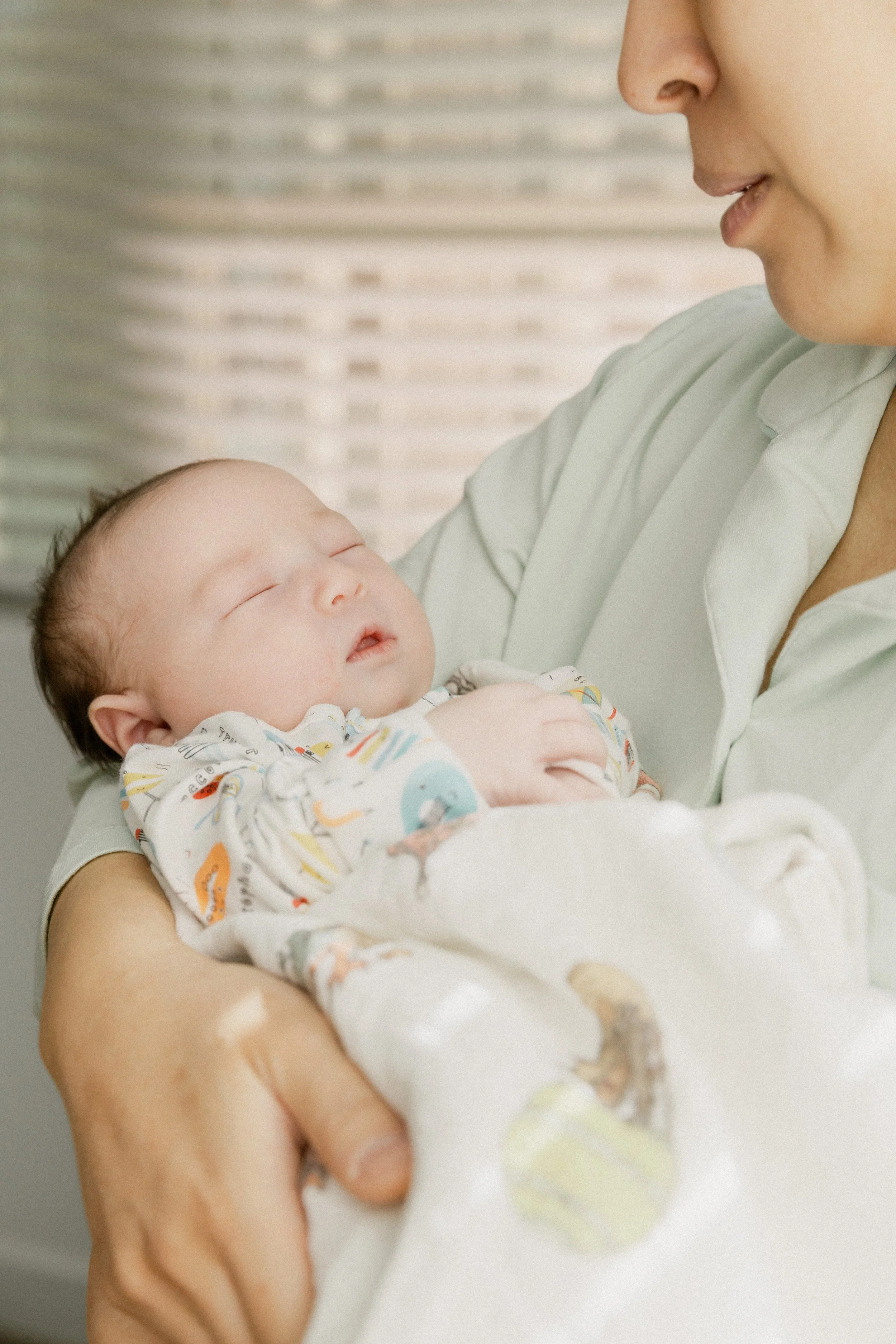 mom holds her newborn near the window during photo shoot in tucson