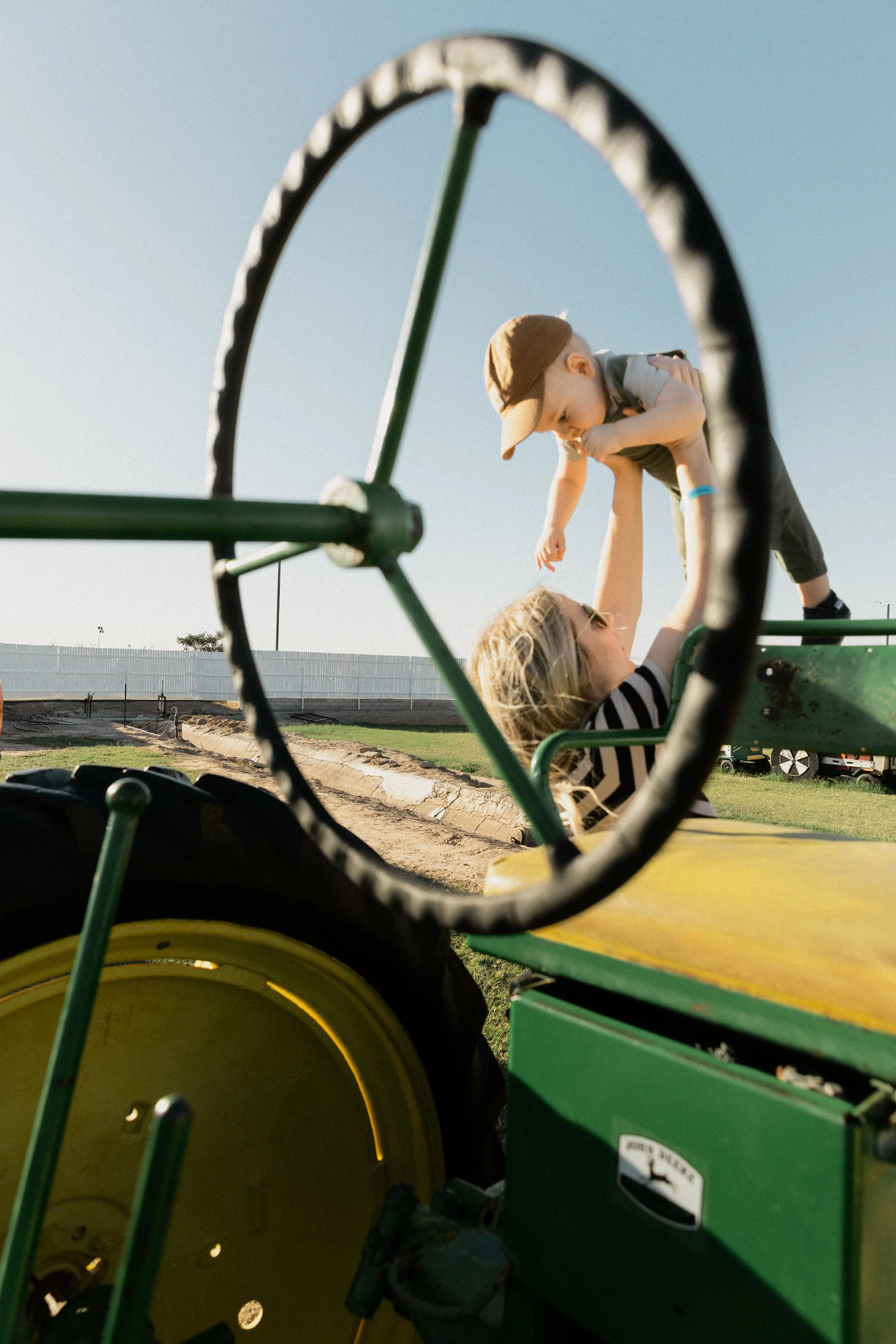 A woman and a young boy playing on a playground, seen through a wheelbarrow frame.