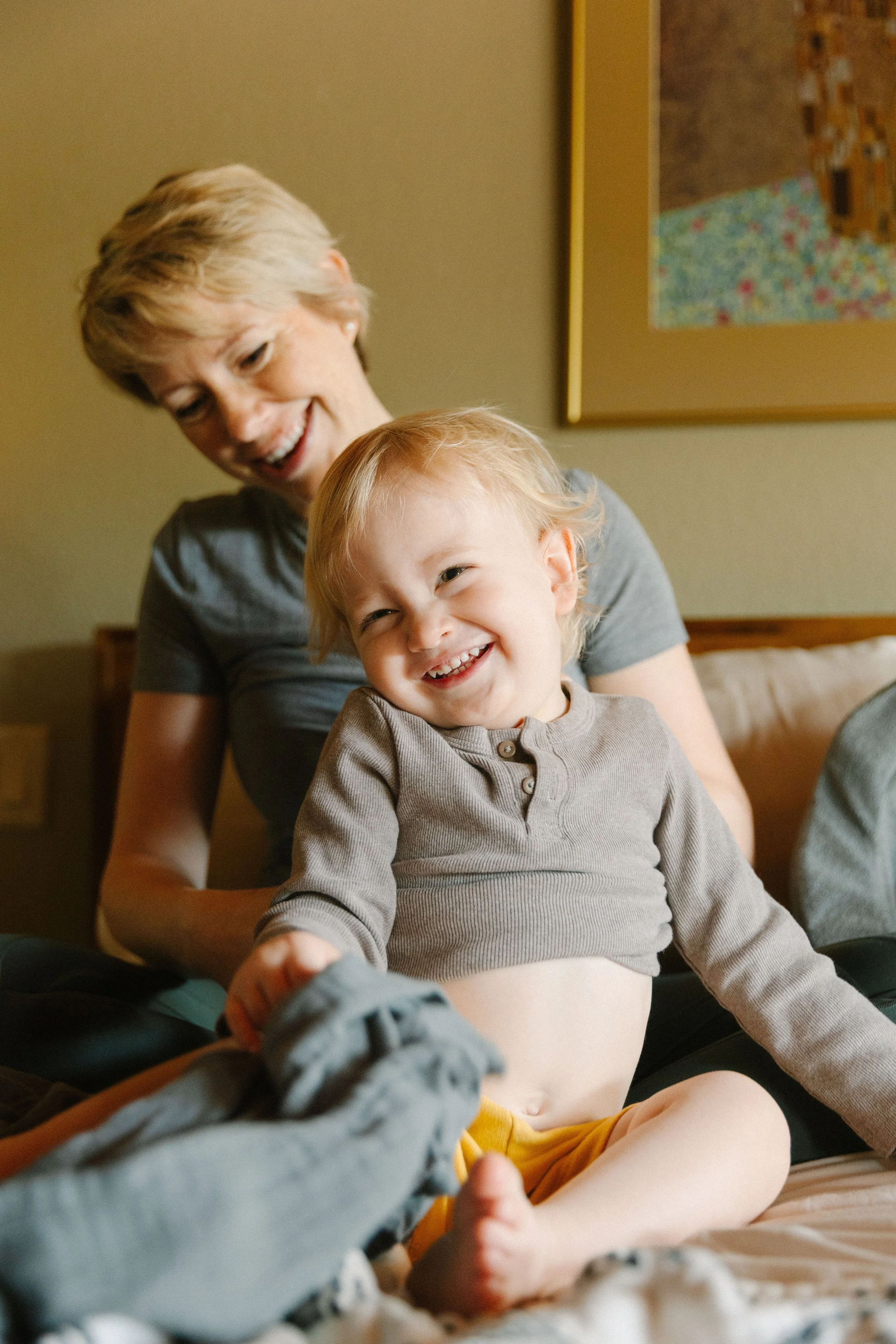 A older woman and a young girl smiling and playing together in a bedroom.