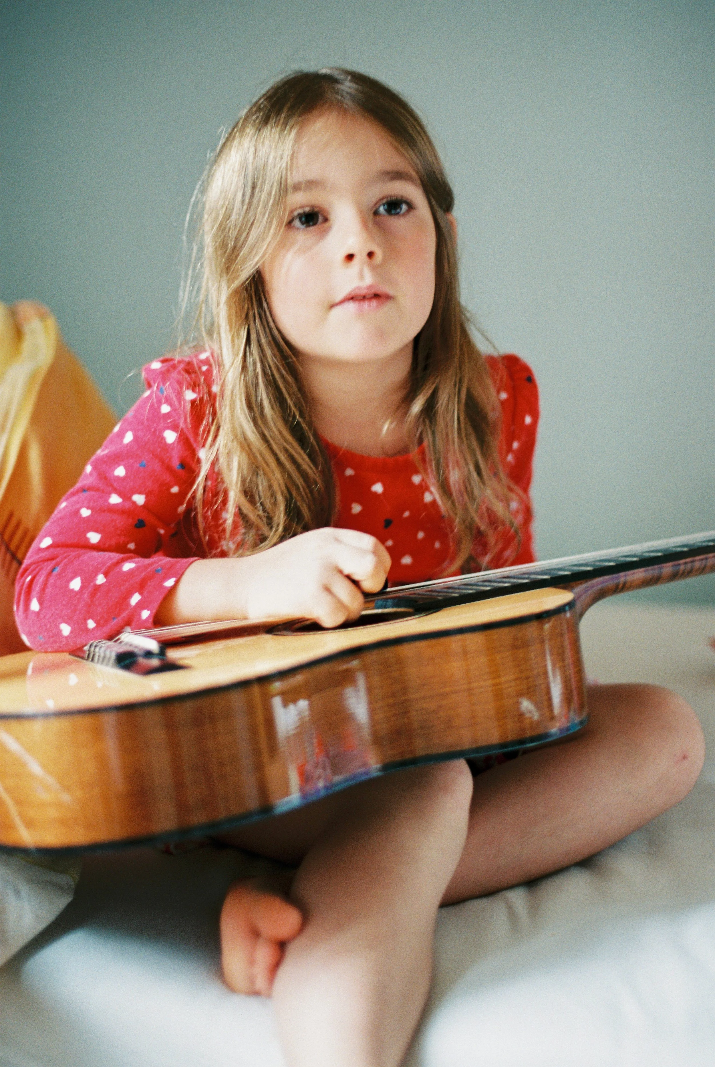 little girl strums guitar at an in home photo session in tucson