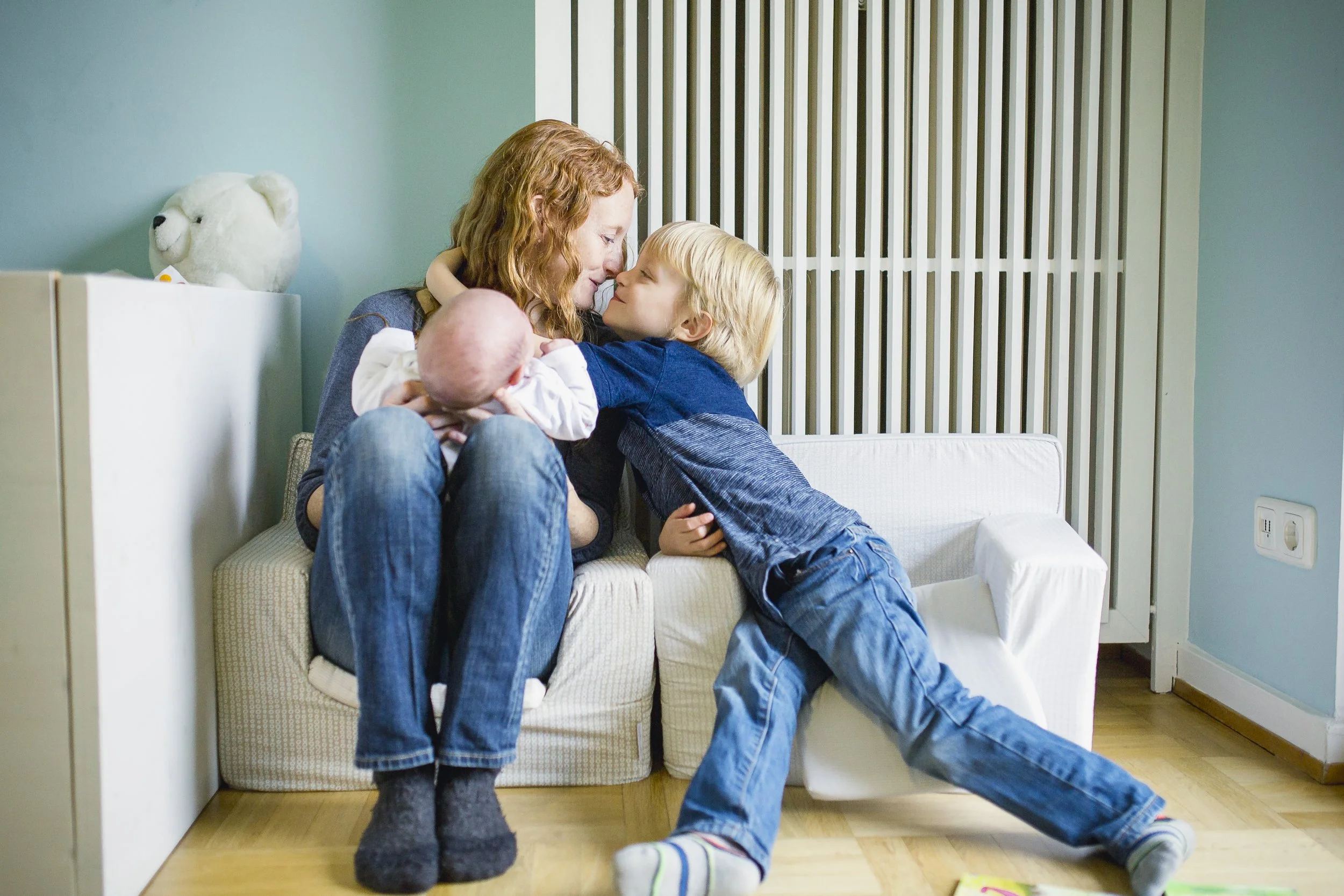 Woman with child and baby sitting on a couch in a cozy room.
