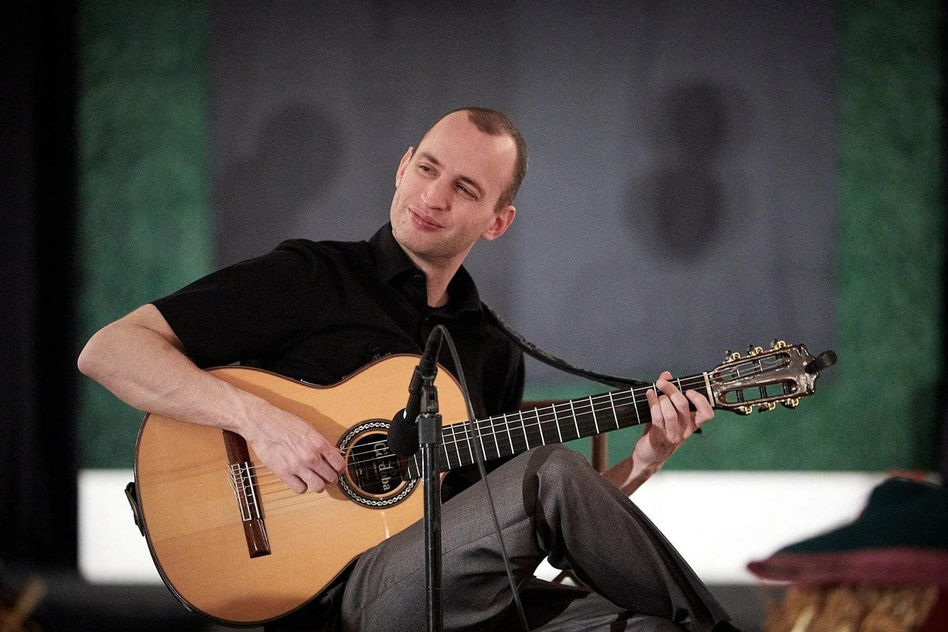 Jim Perona playing classical guitar on stage in formal attire