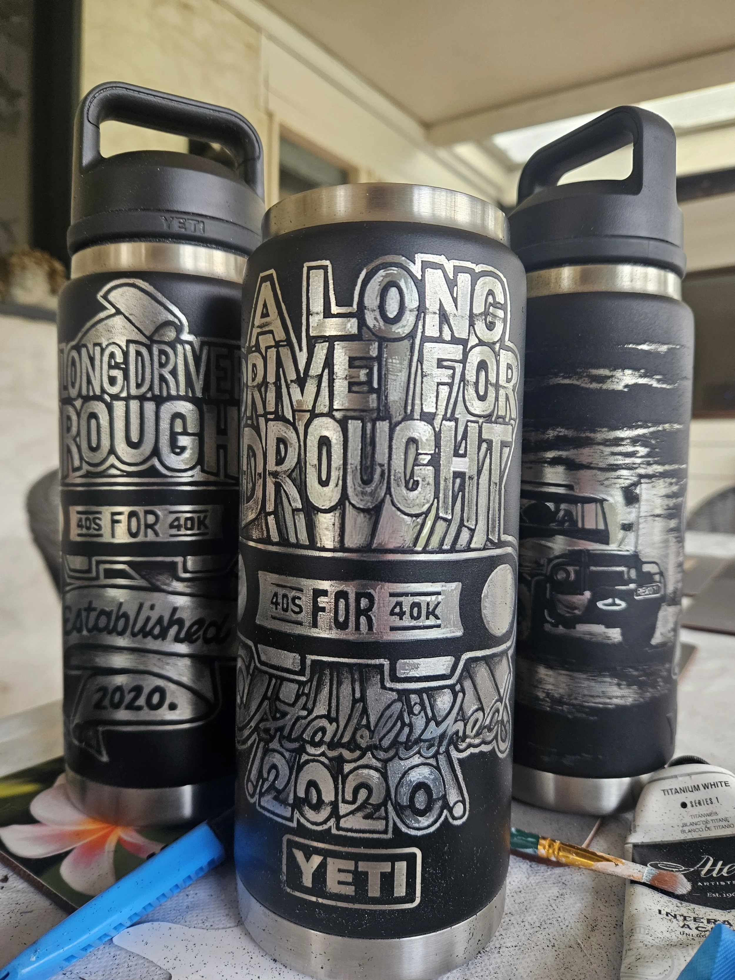 3 of 4 scratch etched water bottles, for a charity called a "Long drive for drought". 2026