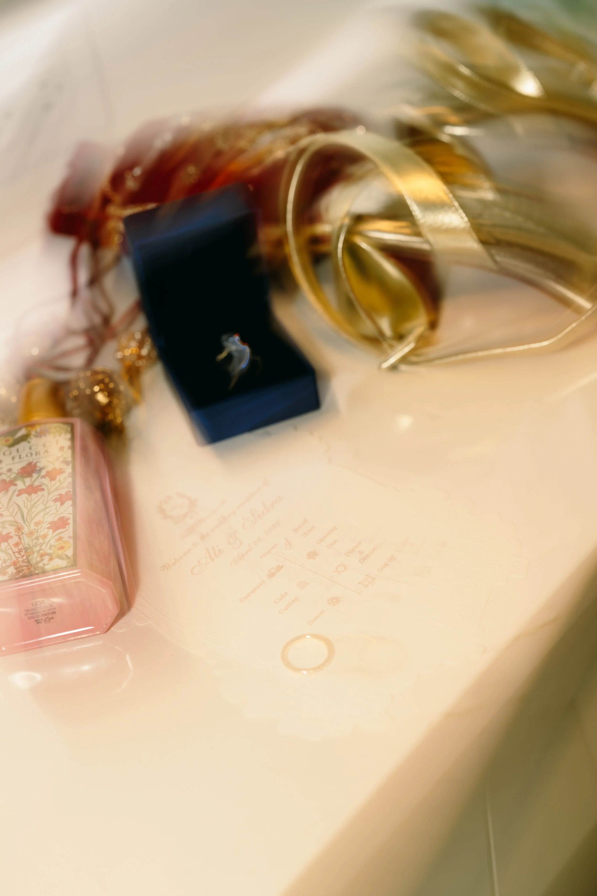 Close-up of a pink and white floral perfume bottle with a black cap on a white surface.