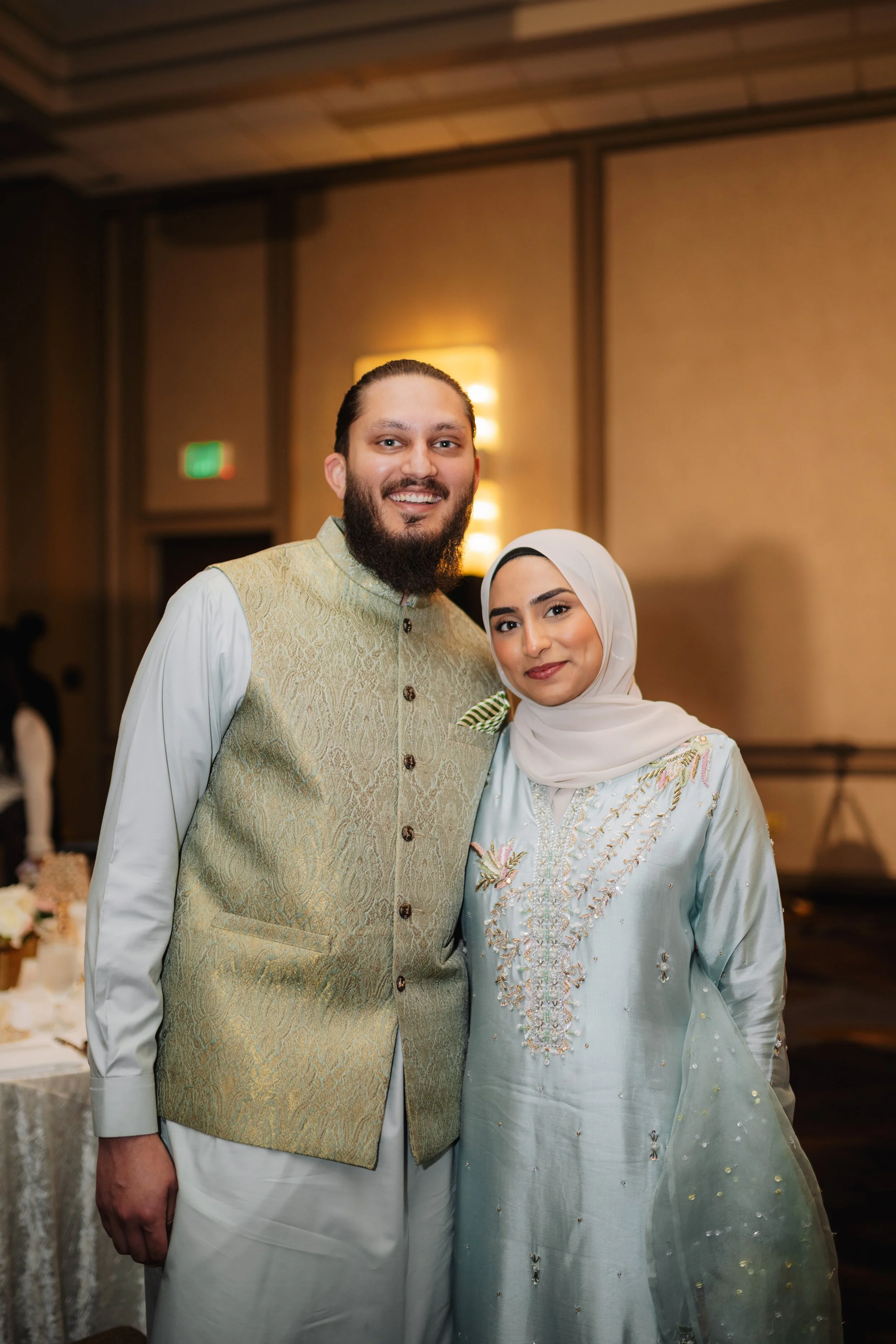 A man and woman dressed in traditional attire at a celebration in a decorated indoor venue.