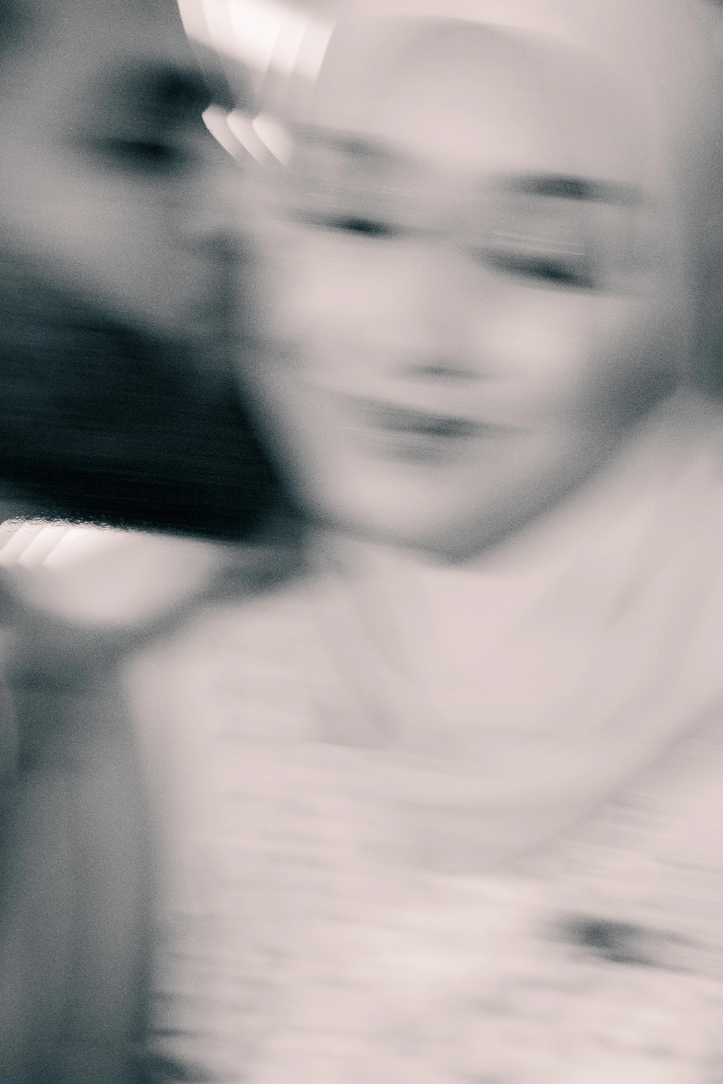 A blurry, close-up photograph of a smiling woman wearing glasses.