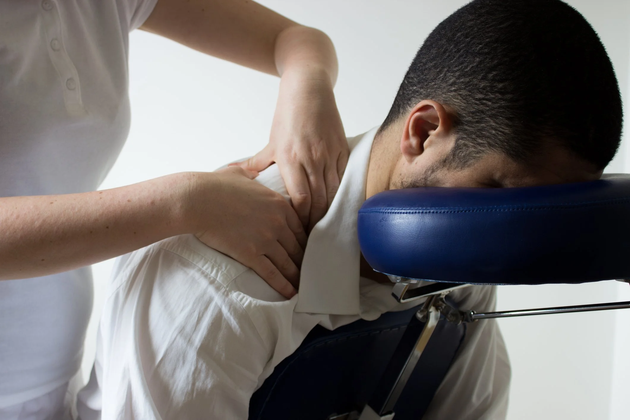 Man receiving a chair massage from trained, Massachusetts licensed and insured Boston Pops Chair Massage Therapist at a Client's office in the Financial District of Boston as part of their Corporate Employee Wellness Program!