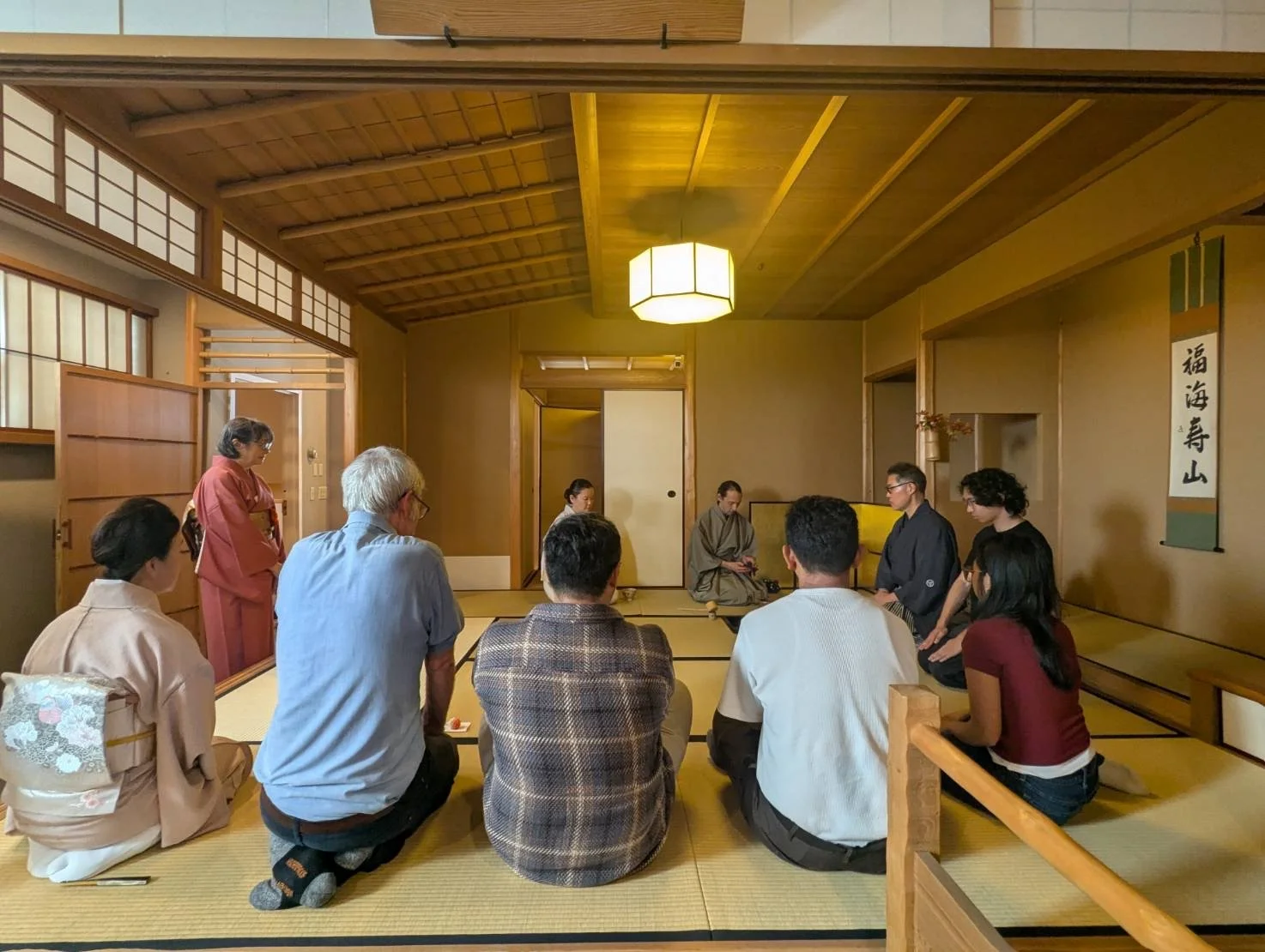 People participating in a traditional Japanese tea ceremony inside a tatami room.
