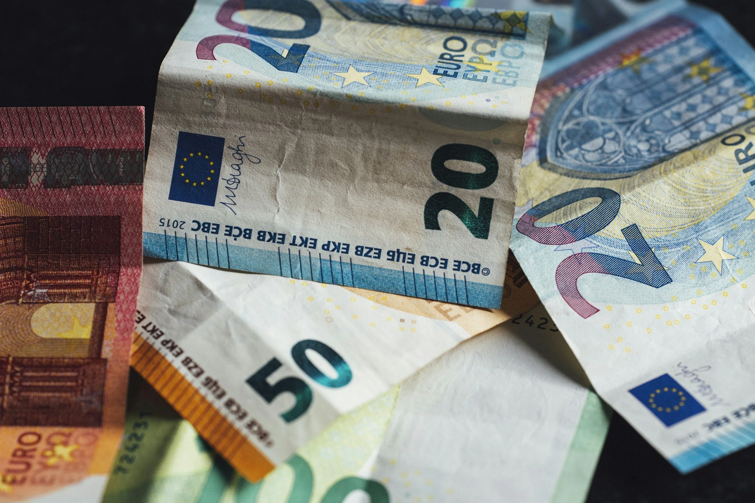 Various crumpled euro banknotes, including 20, 50, and 10 euro bills.