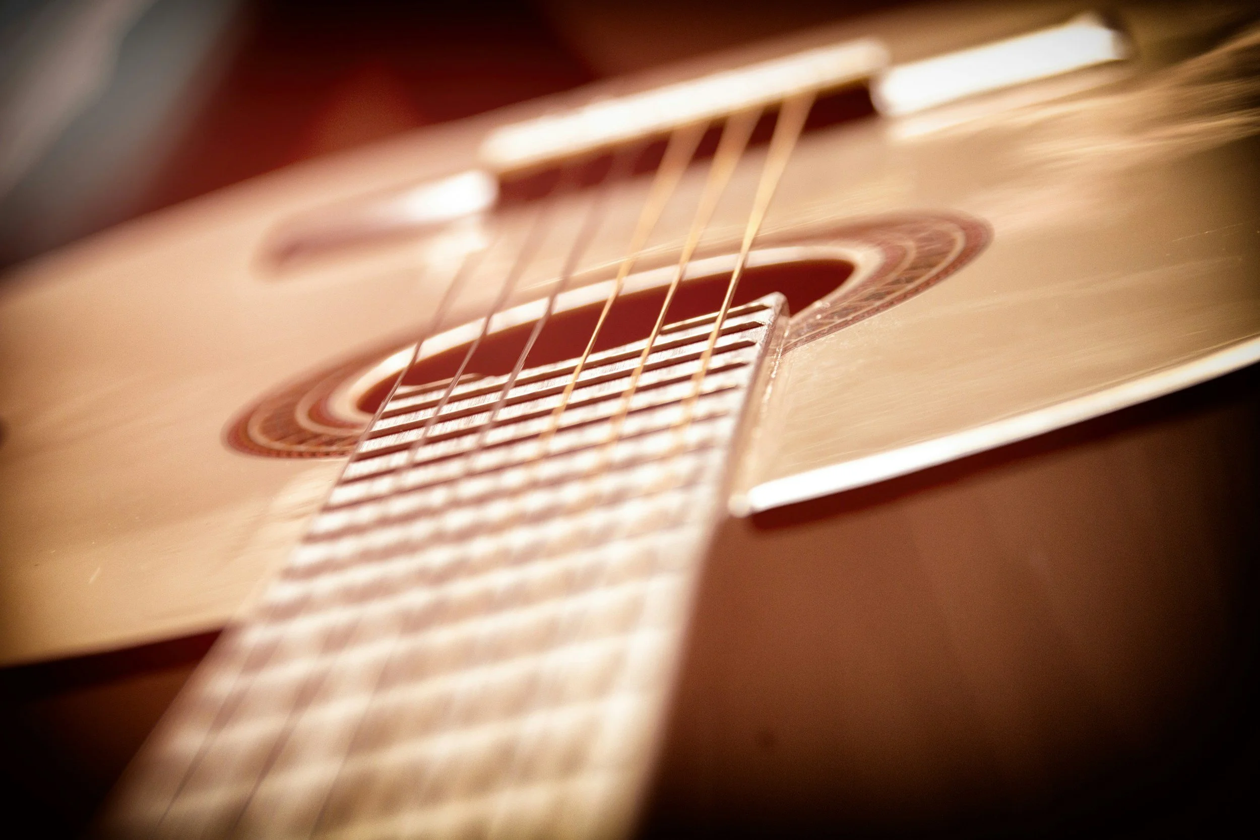 Close-up of a wooden acoustic guitar, showing the sound hole and strings.