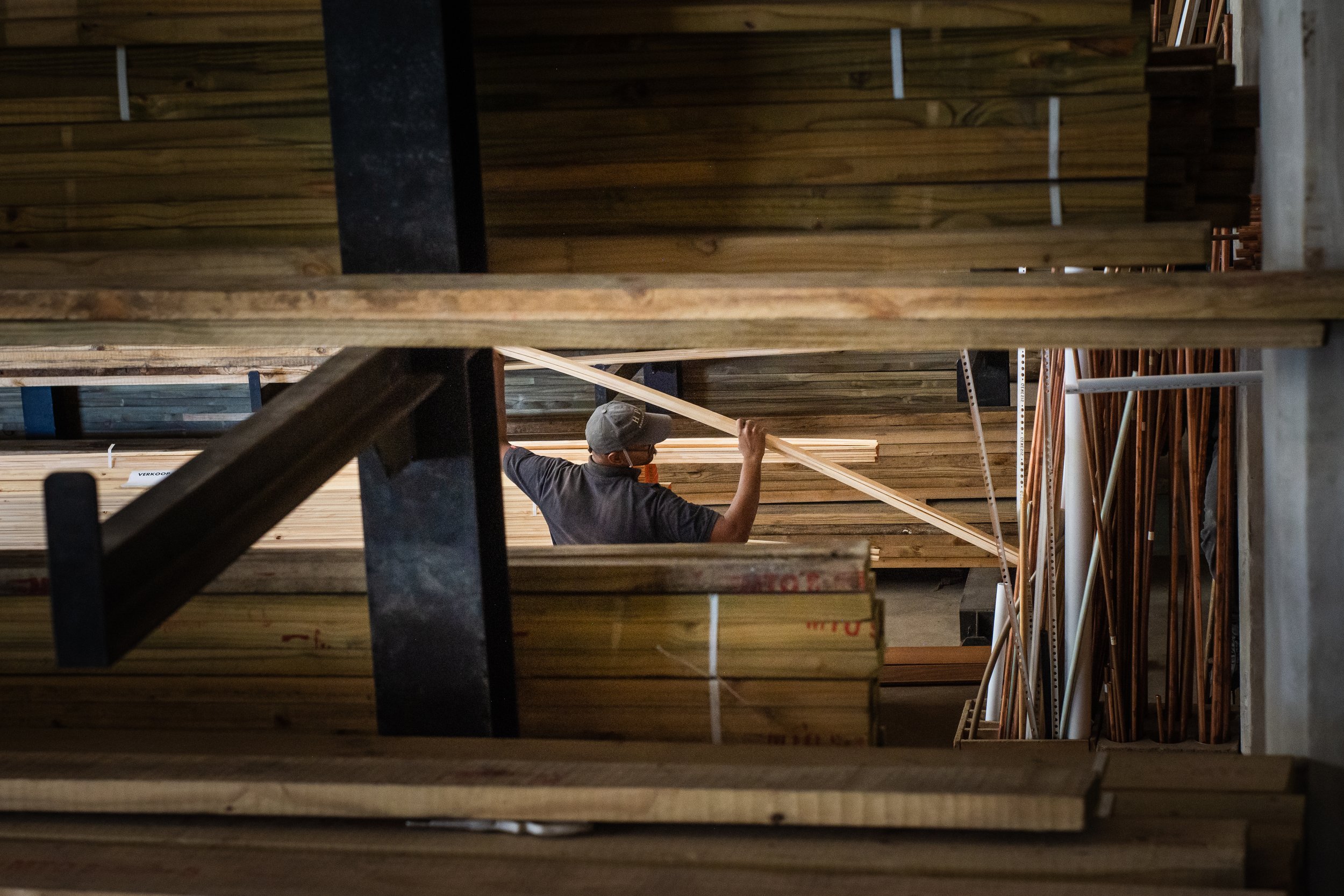 Person selecting wooden planks in a lumber storage area.