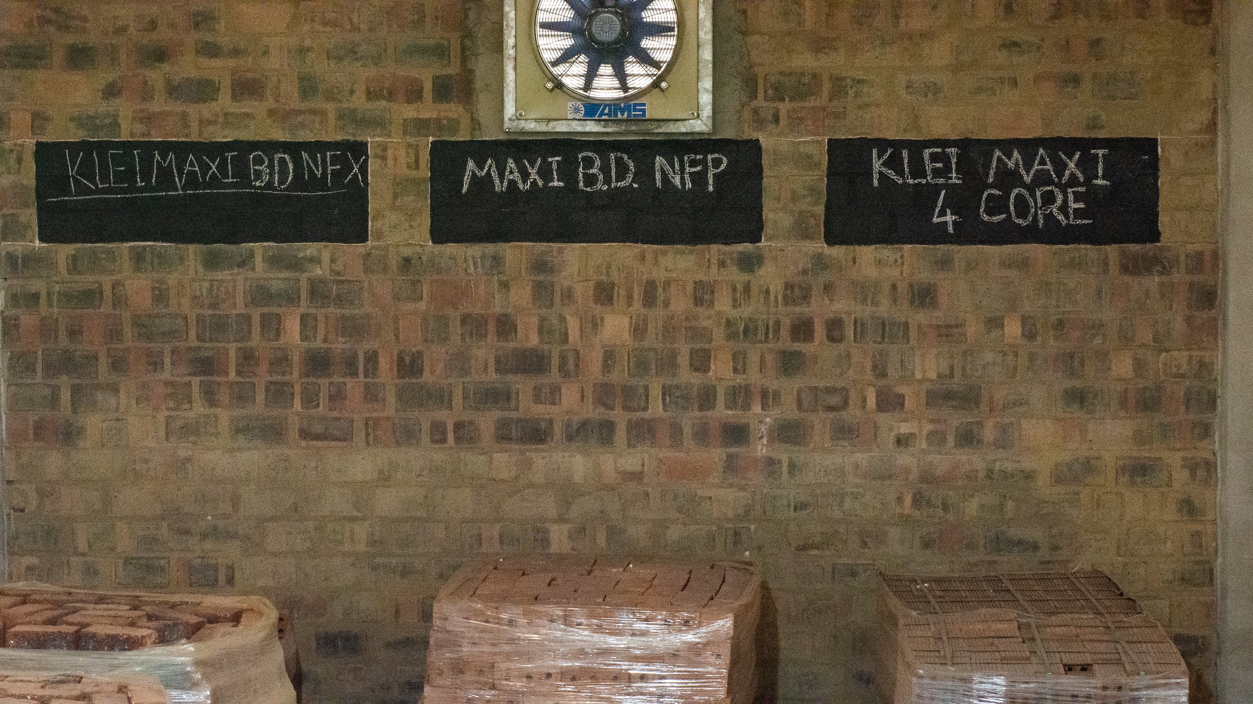 Wall with graffiti-like chalk writing and stacked bricks in a warehouse.