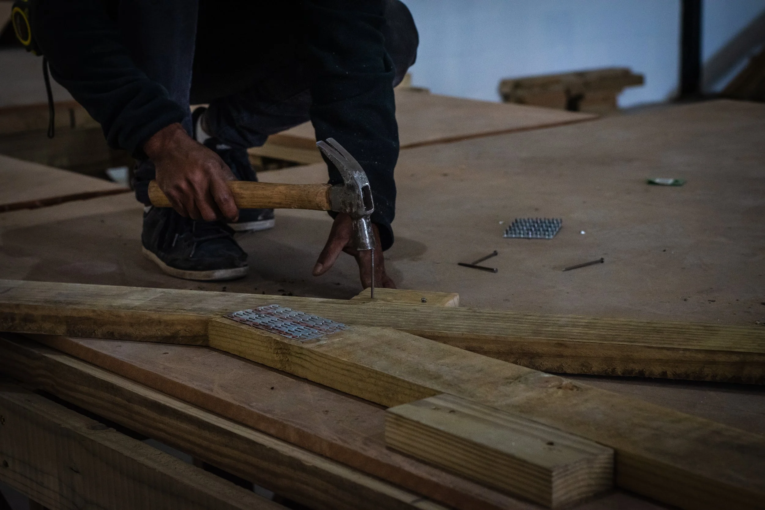 Person hammering nail into wood on construction site