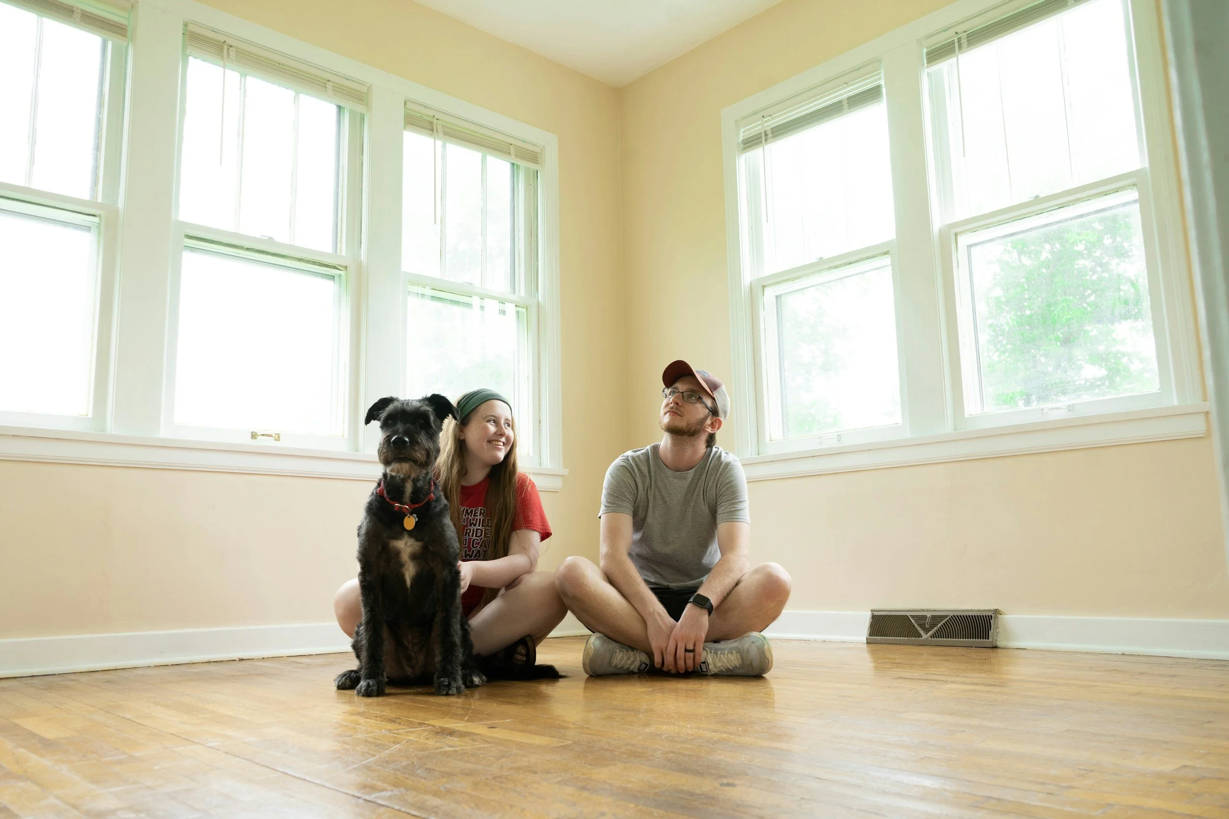Young couple with their dog, sitting on the floor in an empty living room